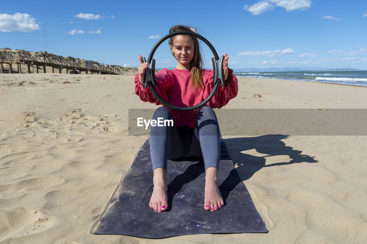 Woman with pilates ring on the beach