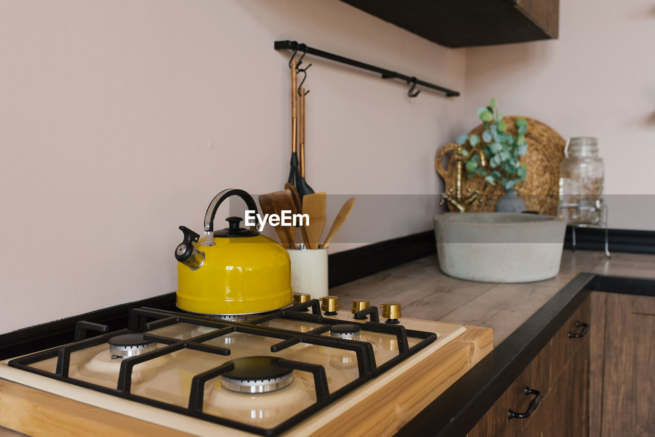 Yellow kettle on a gas stove in the wooden kitchen of a country house 