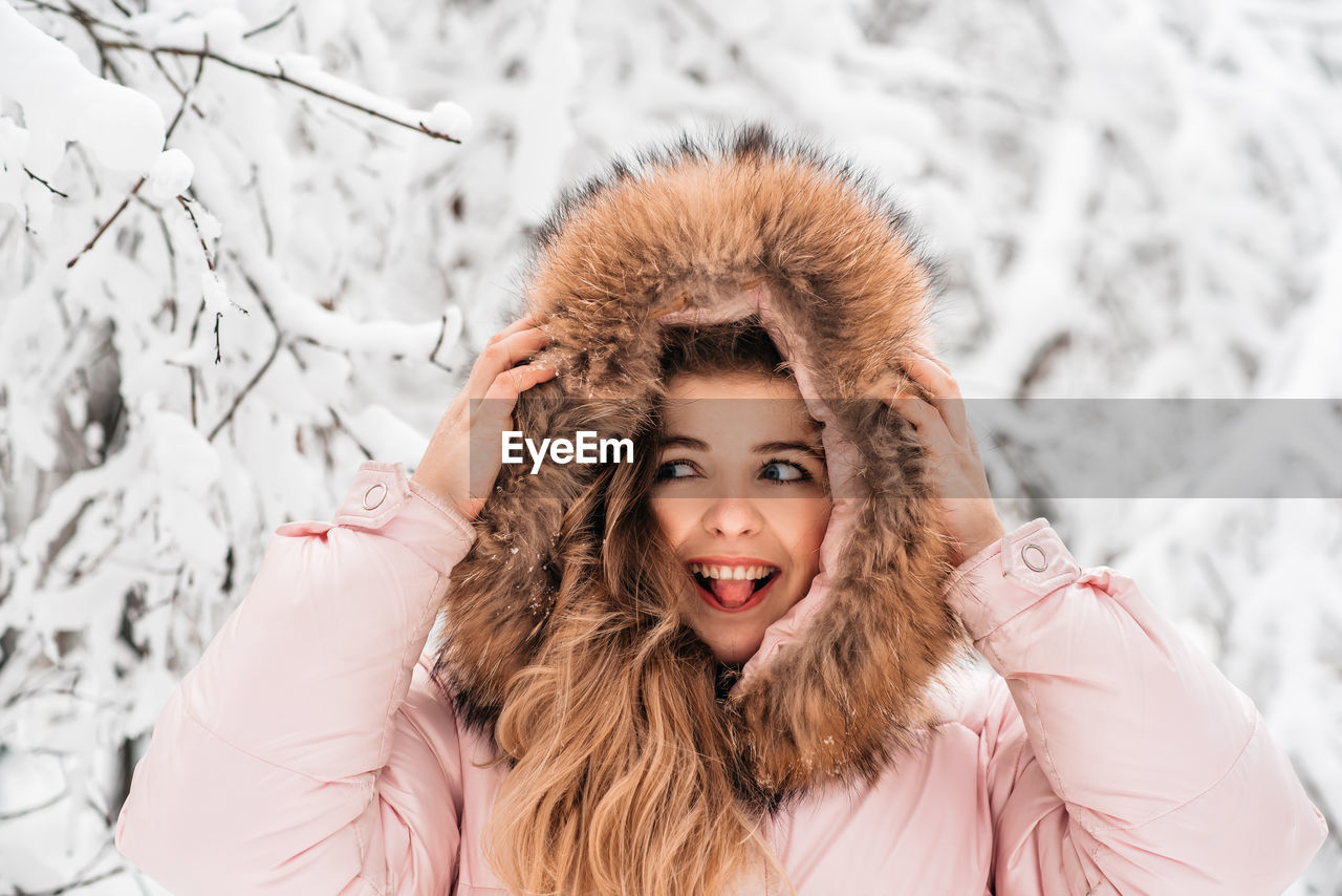 PORTRAIT OF A SMILING YOUNG WOMAN WITH SNOW