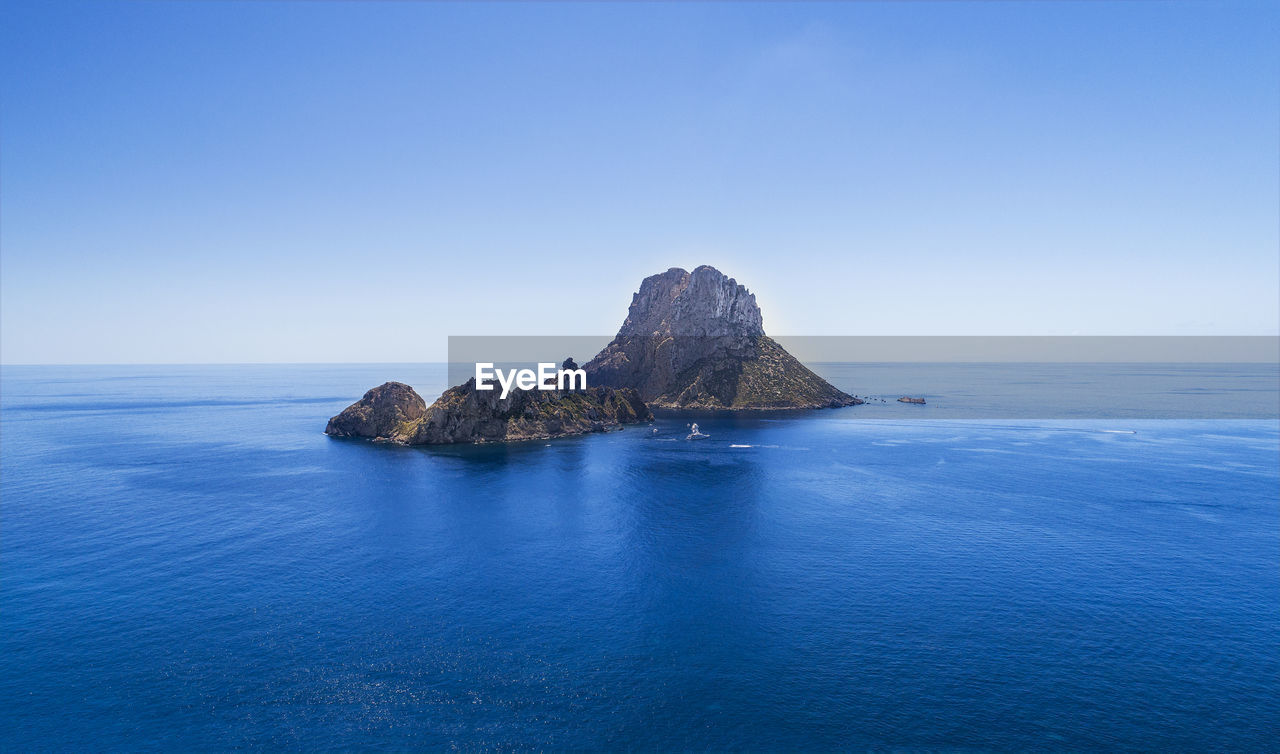 SCENIC VIEW OF ROCK FORMATION IN SEA AGAINST CLEAR BLUE SKY