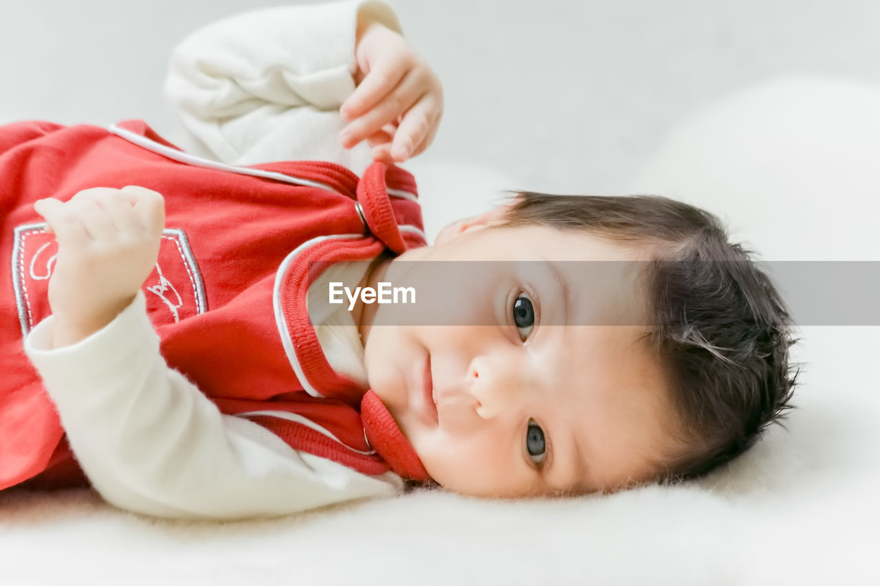 Portrait of cute baby lying on bed at home