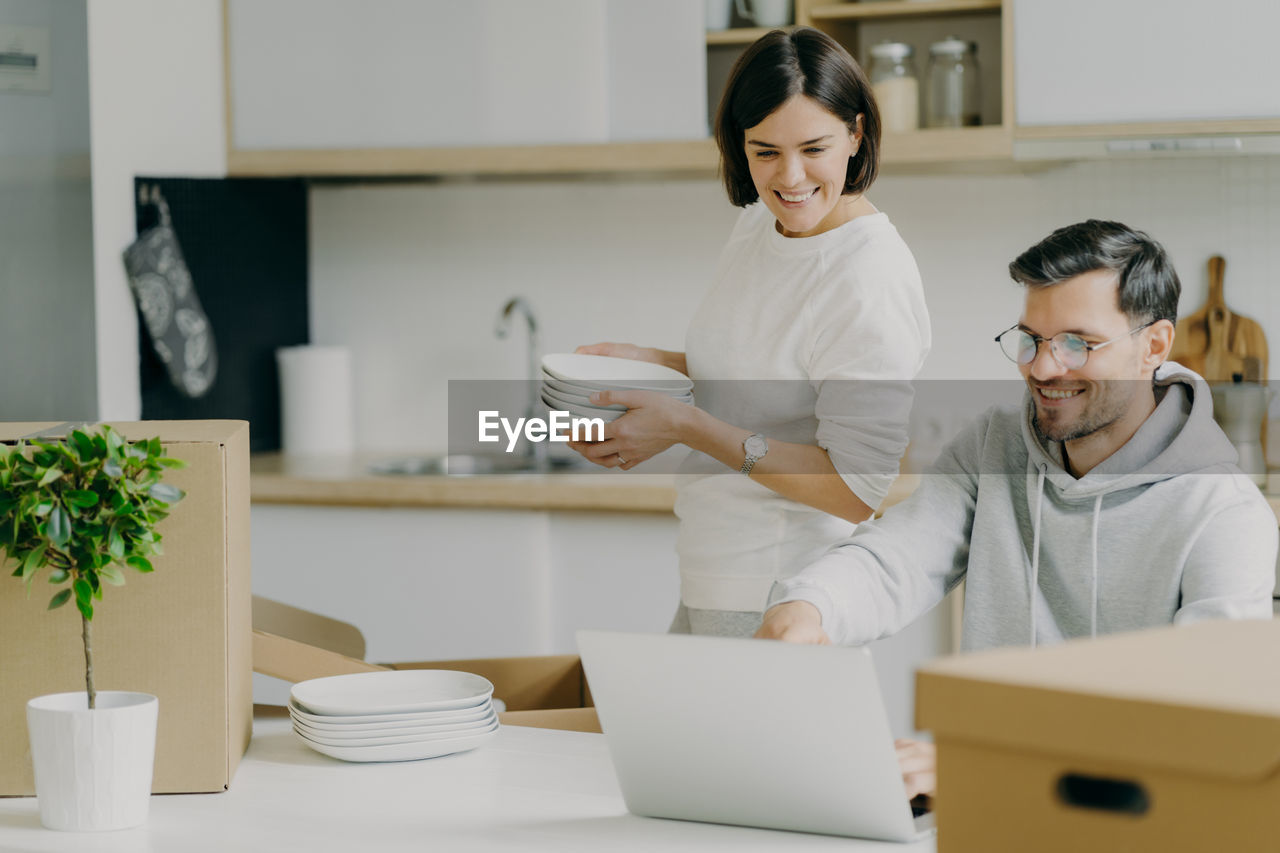 Smiling couple looking at laptop at new home