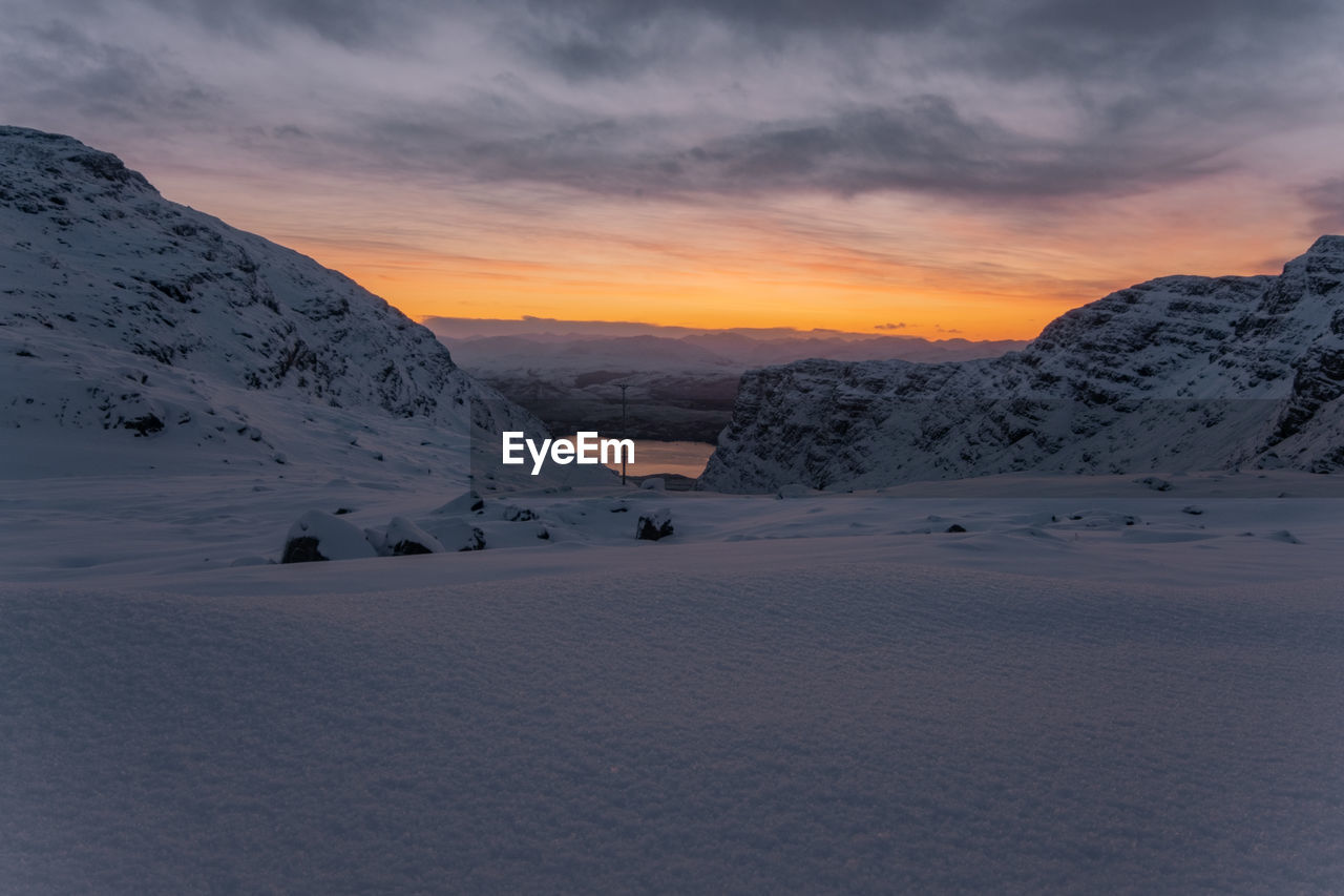 Scenic view of snow covered mountains against sky during sunset