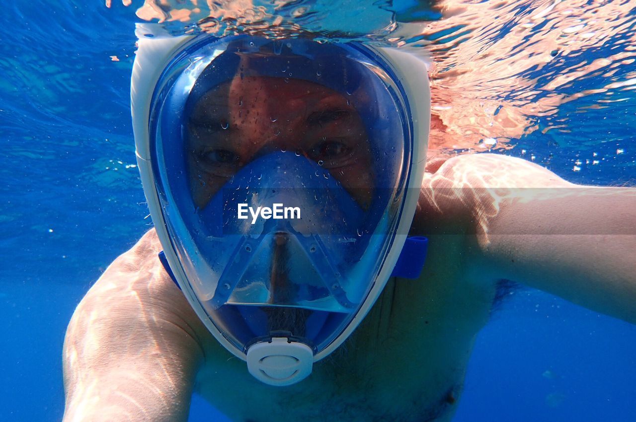 Close-up of shirtless man snorkeling in sea