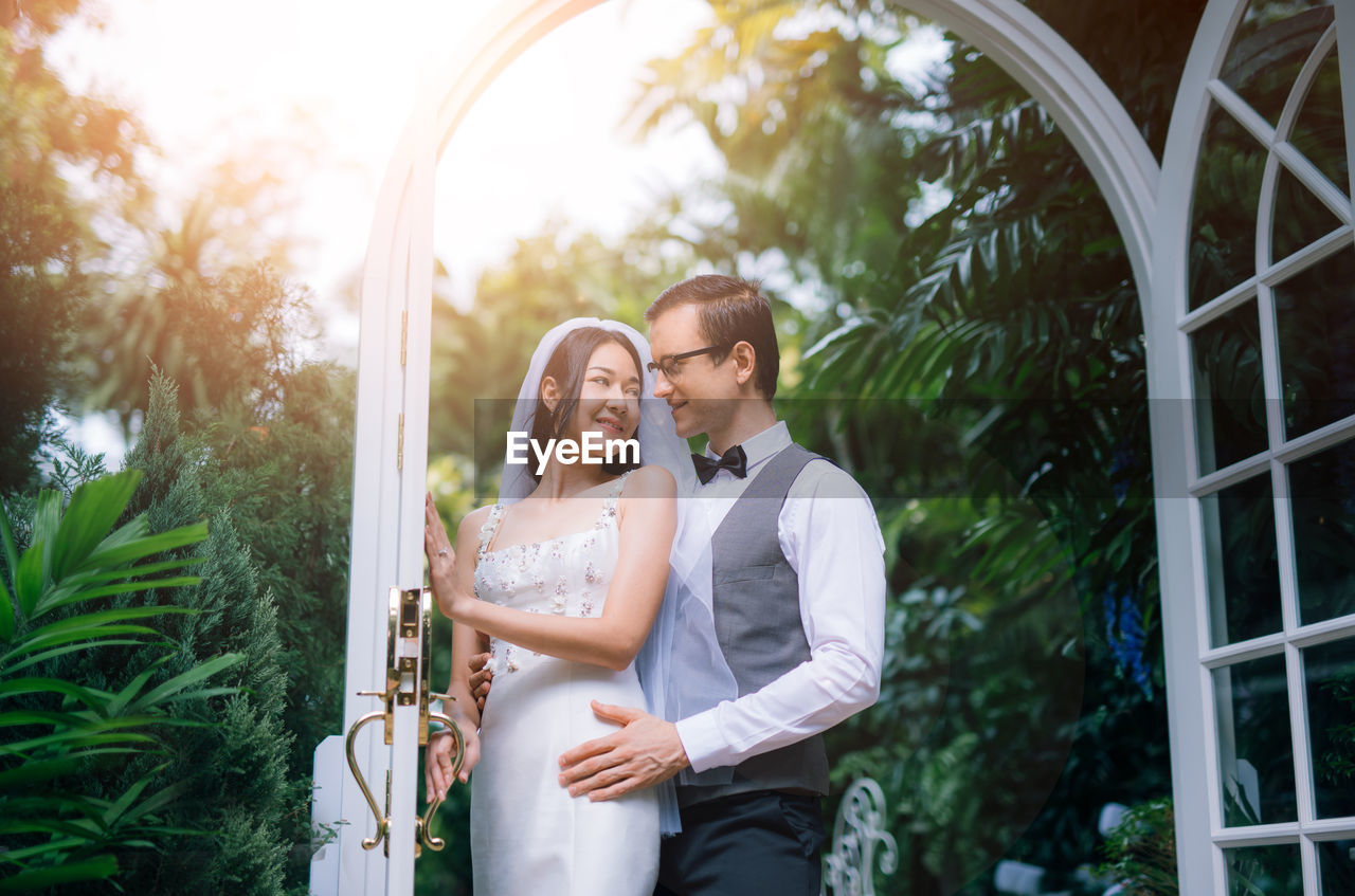 Loving wedding couple standing at backyard