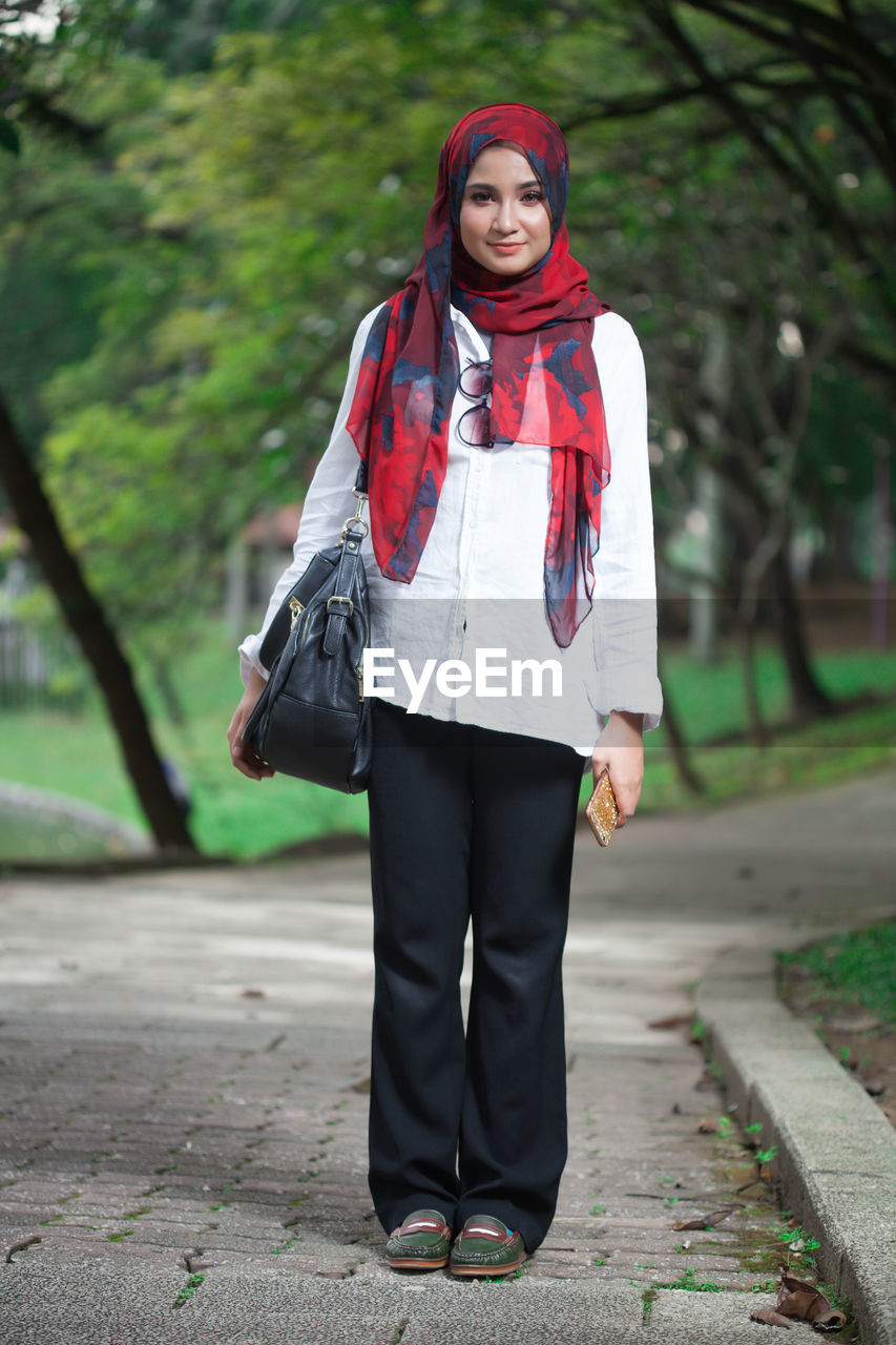 Young woman standing on footpath at park