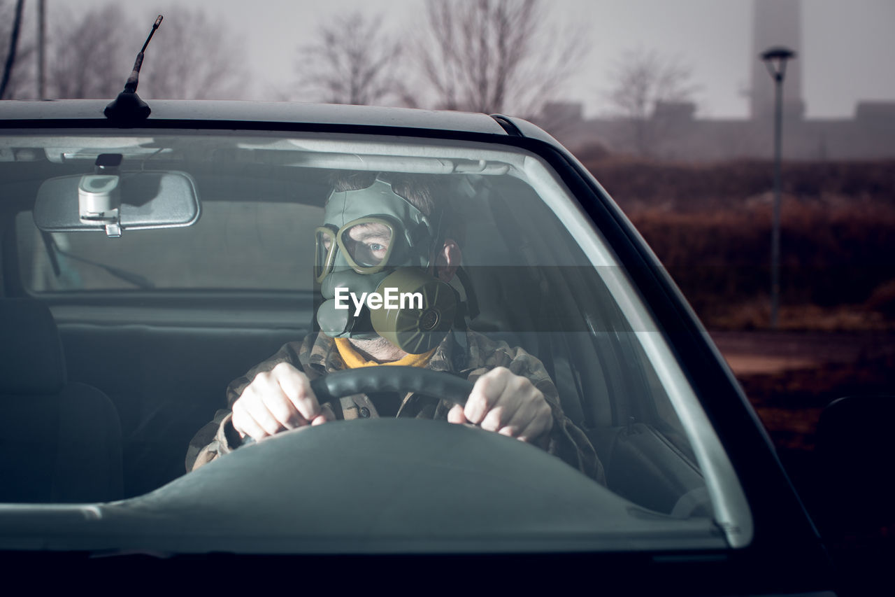 Soldier wearing gas mask driving car