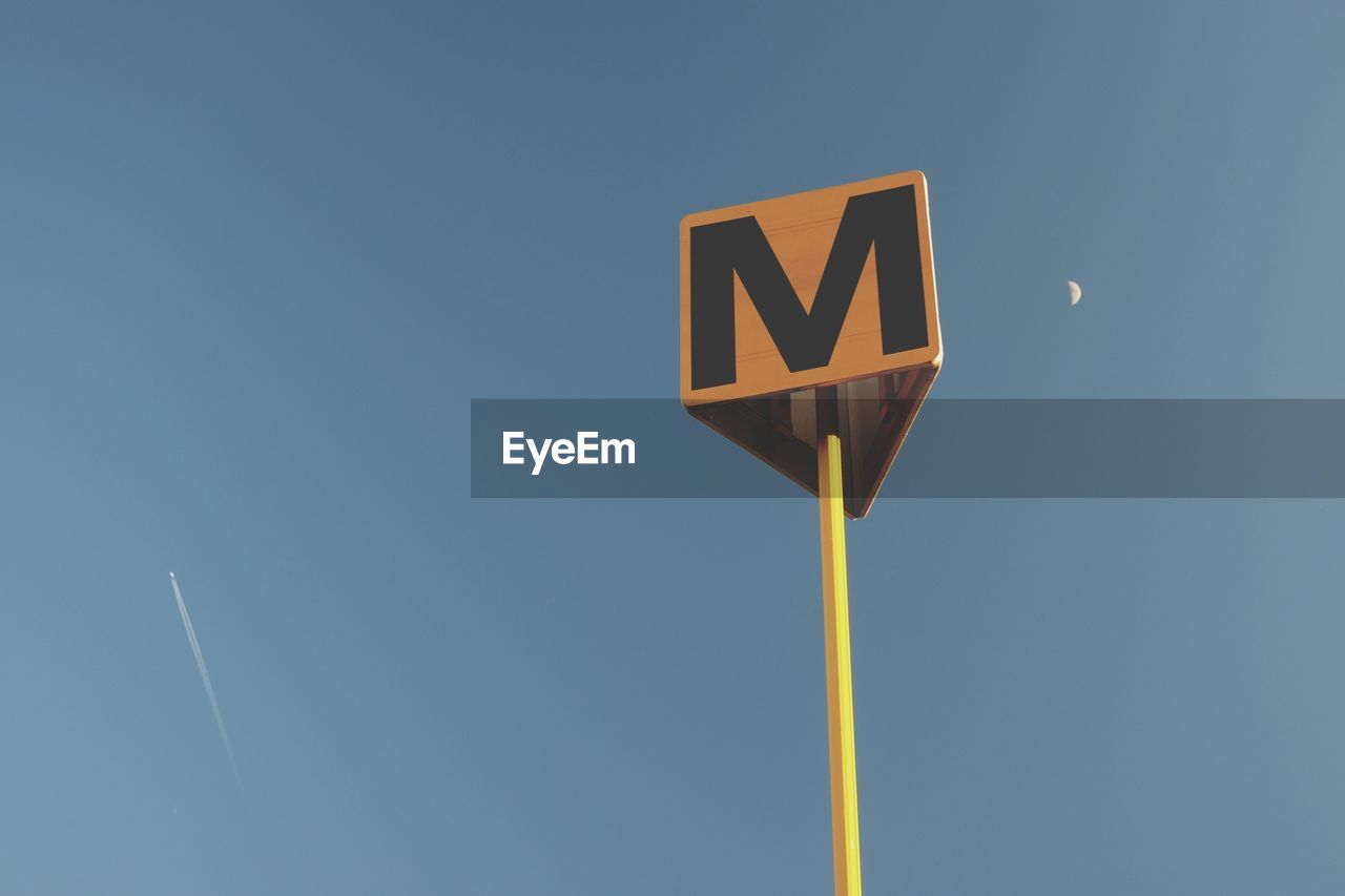 Low angle view of road sign against blue sky