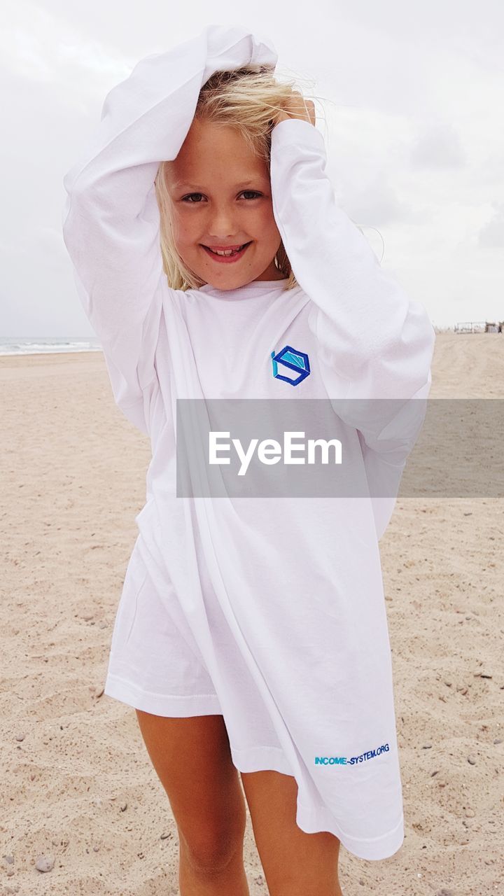 PORTRAIT OF SMILING GIRL ON SAND