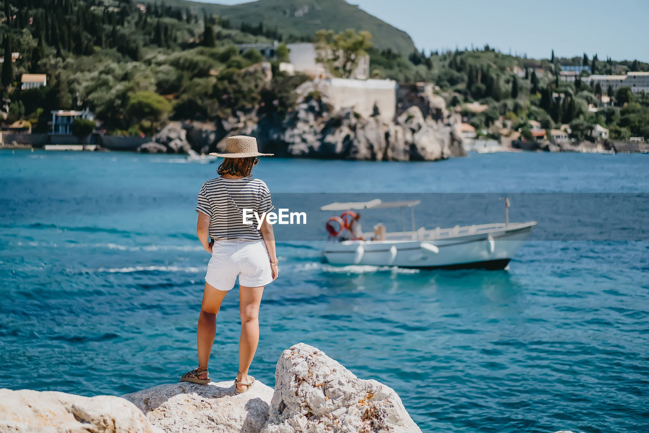 Rear view of man standing on rock by sea