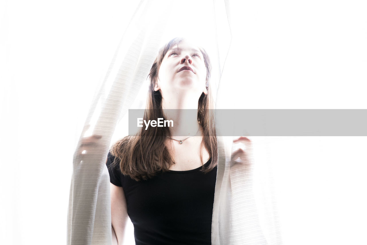 PORTRAIT OF BEAUTIFUL YOUNG WOMAN AGAINST WHITE BACKGROUND