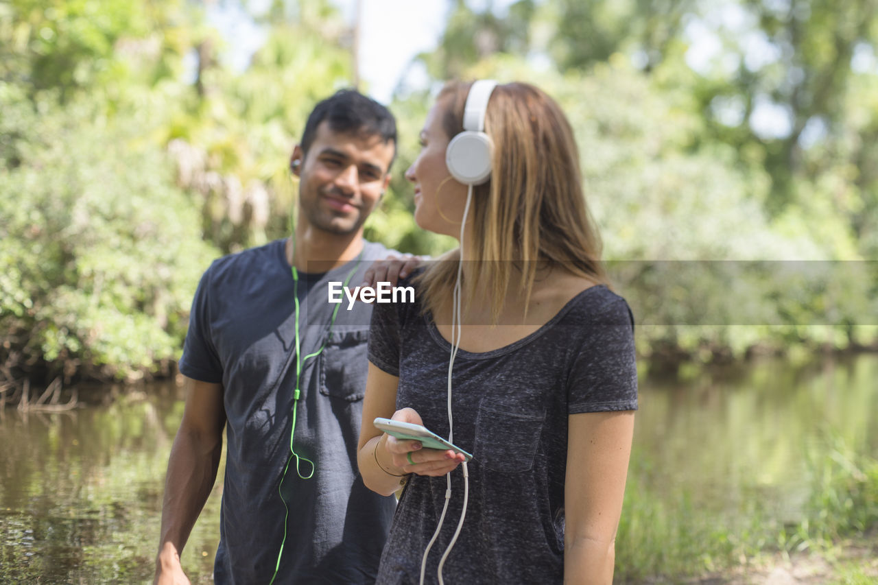 People listening music while standing against lake