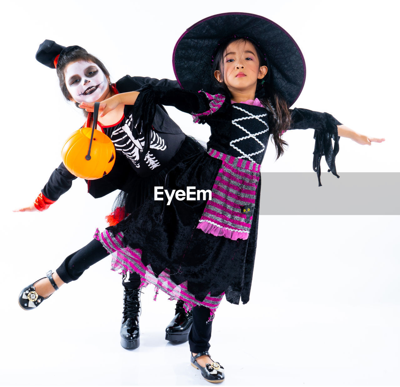 Portrait pair of little girls in halloween and carnival costume isolated on white background