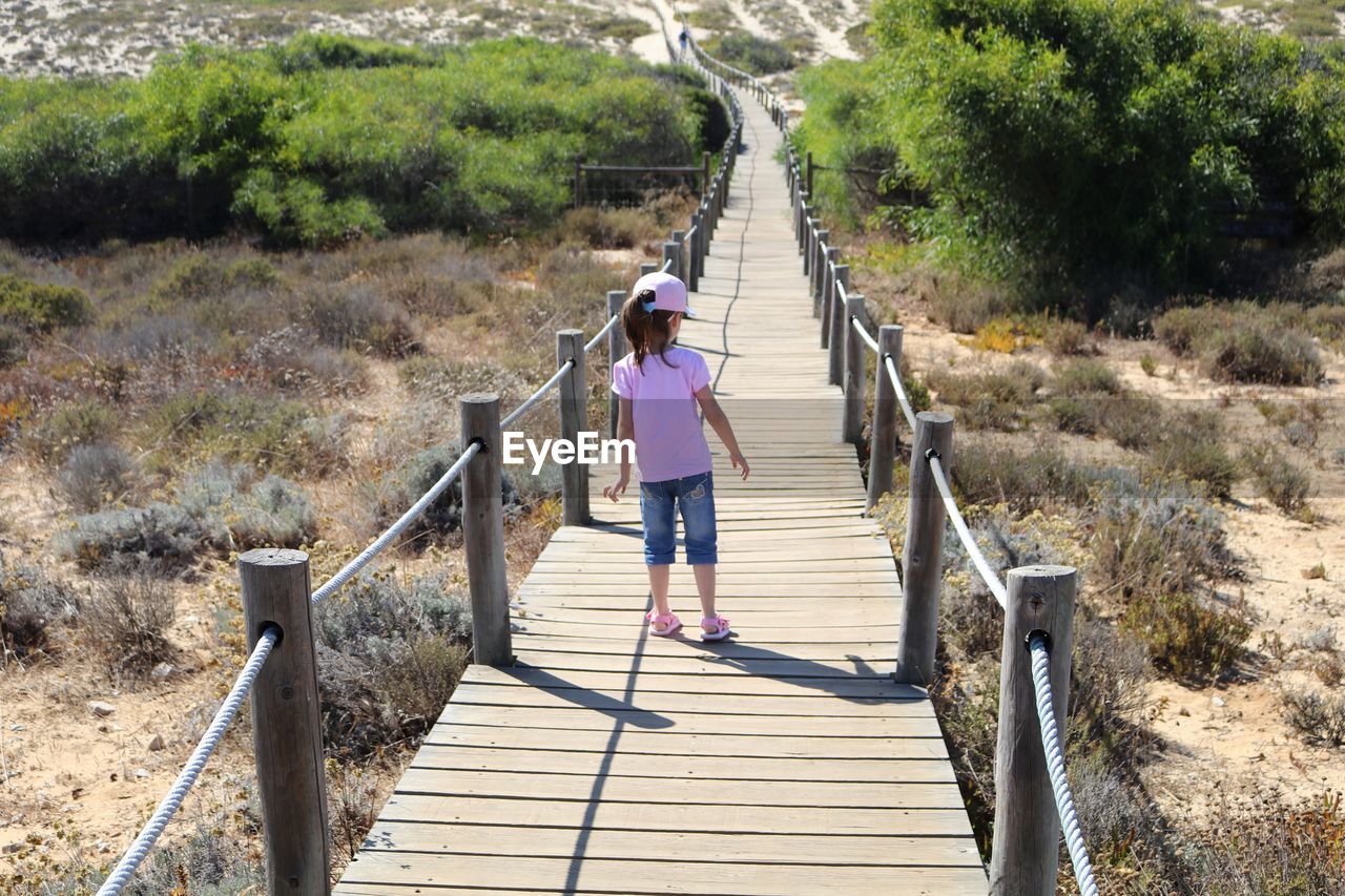 Rear view full length of girl standing on boardwalk