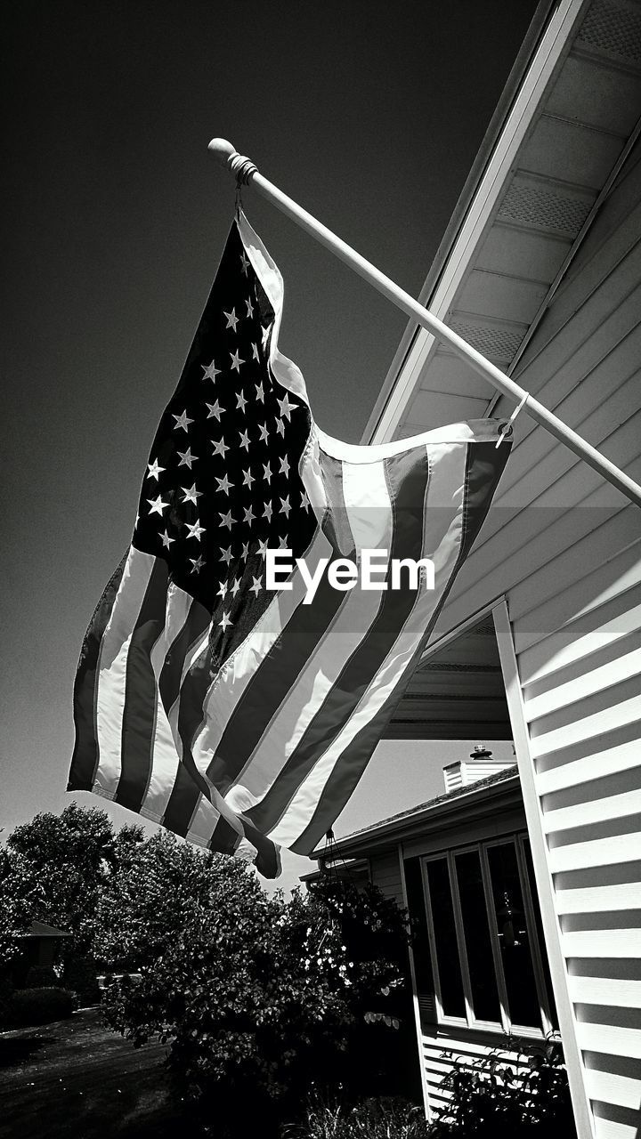 LOW ANGLE VIEW OF FLAG AGAINST BUILT STRUCTURE