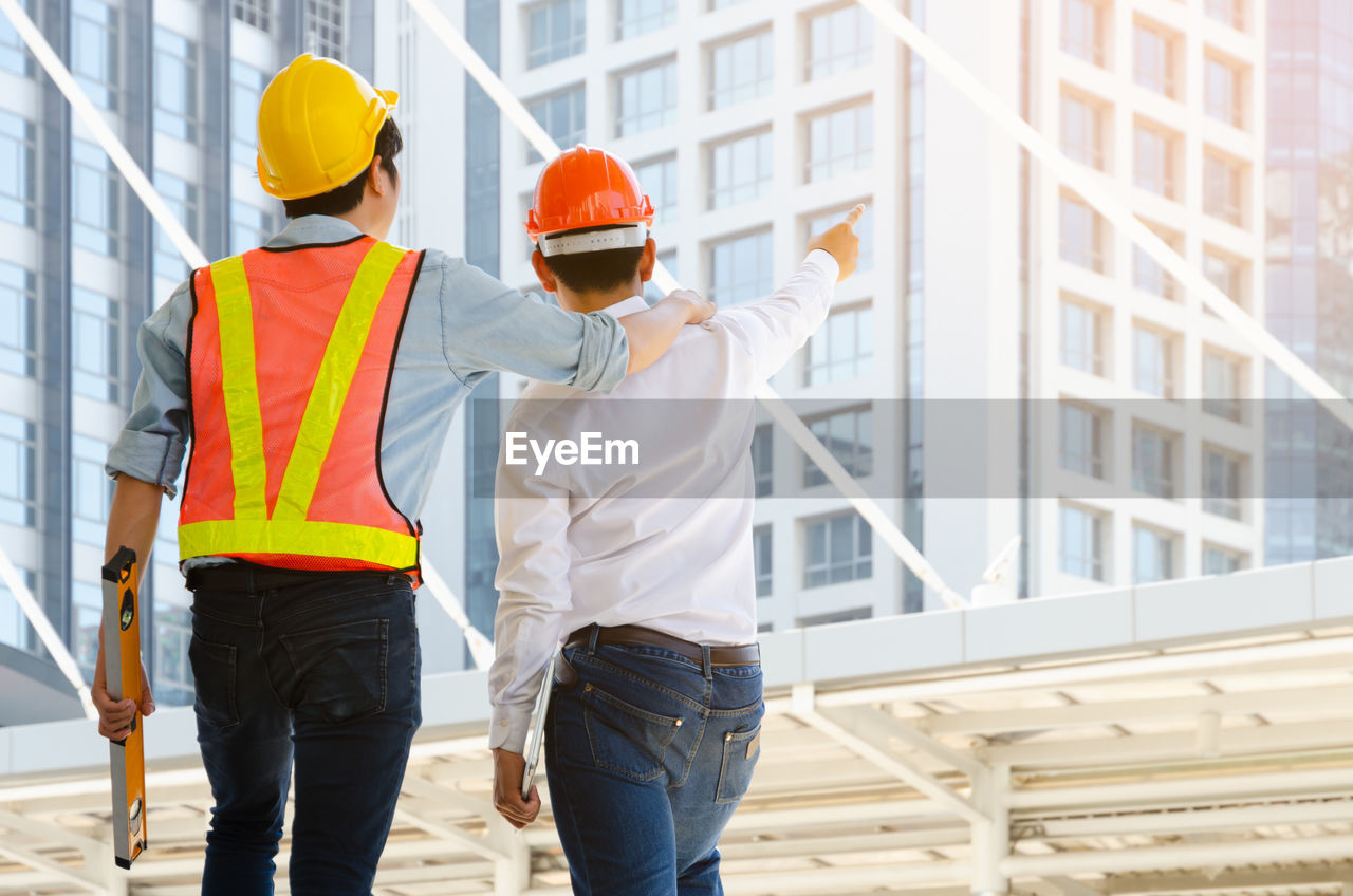 REAR VIEW OF PEOPLE WORKING AT CONSTRUCTION SITE