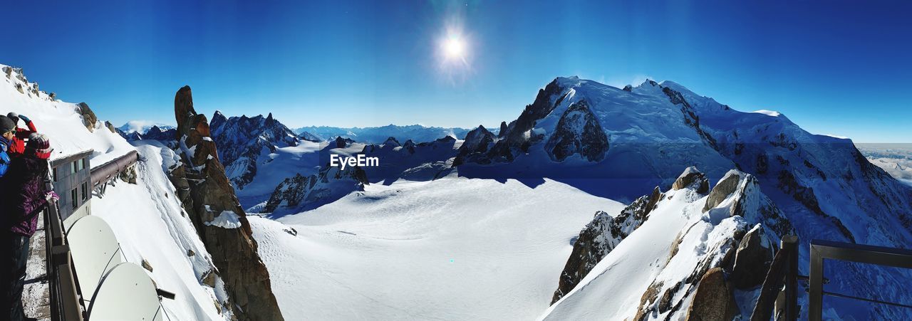 Panoramic view of snowcapped mountains against blue sky