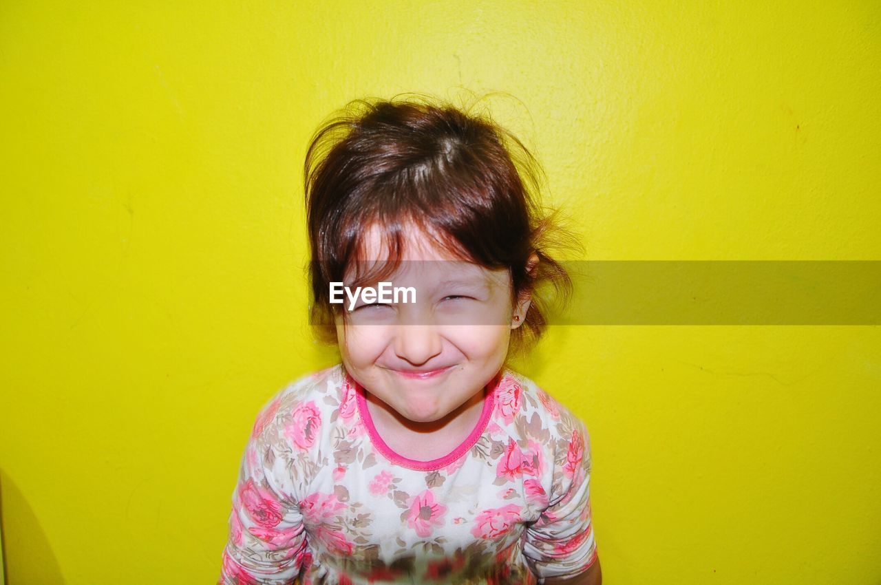 PORTRAIT OF SMILING WOMAN AGAINST YELLOW WALL