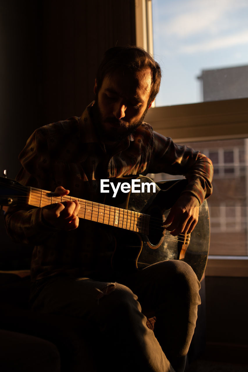 Man playing guitar at home