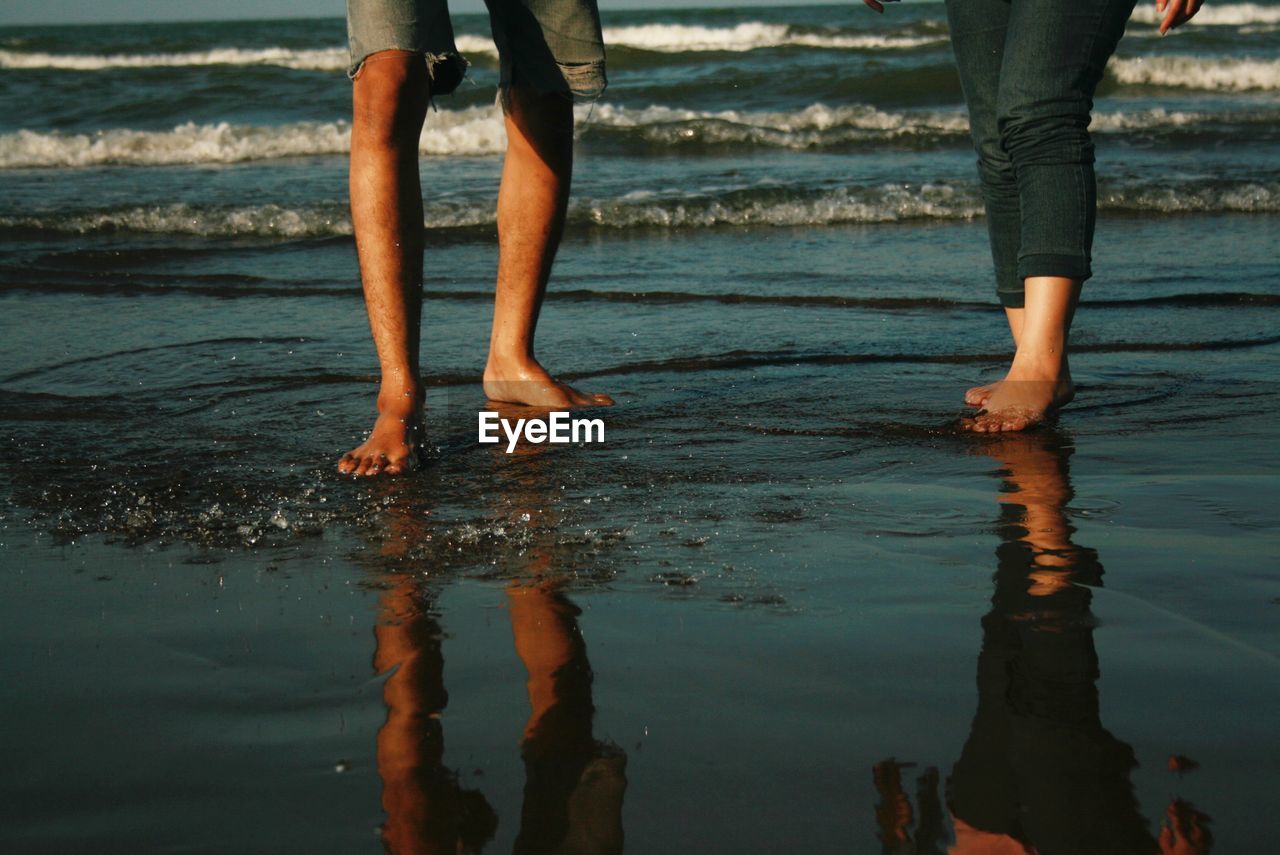 Low section of people standing on beach