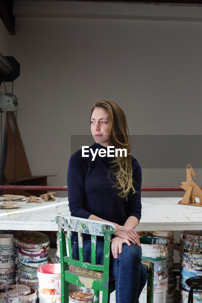 Thoughtful artist sitting on chair at table in art studio