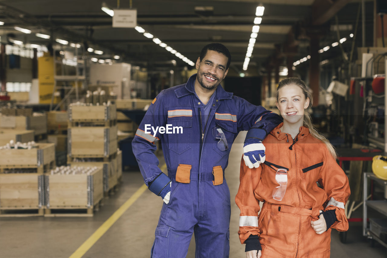 Portrait of smiling male and female coworkers in factory warehouse