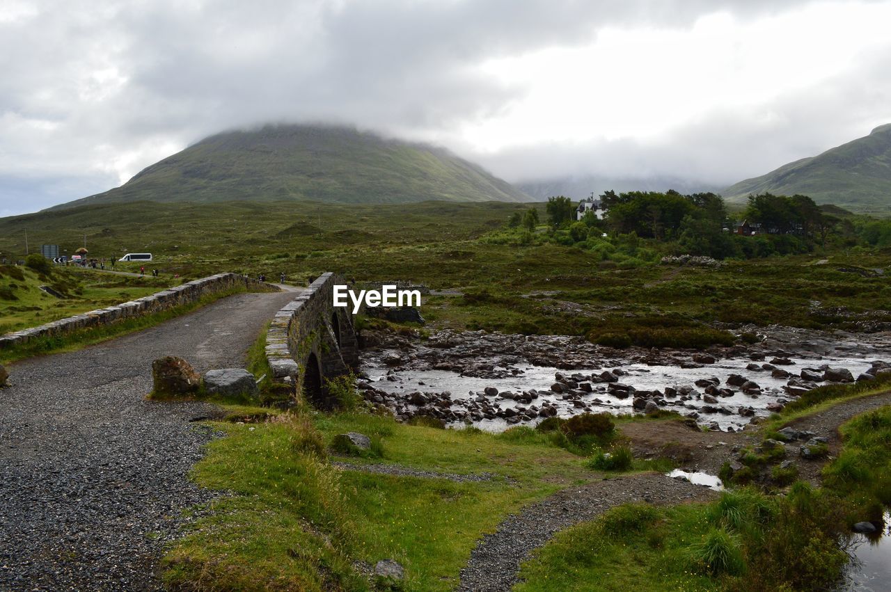 Scenic view of stream by mountains against sky