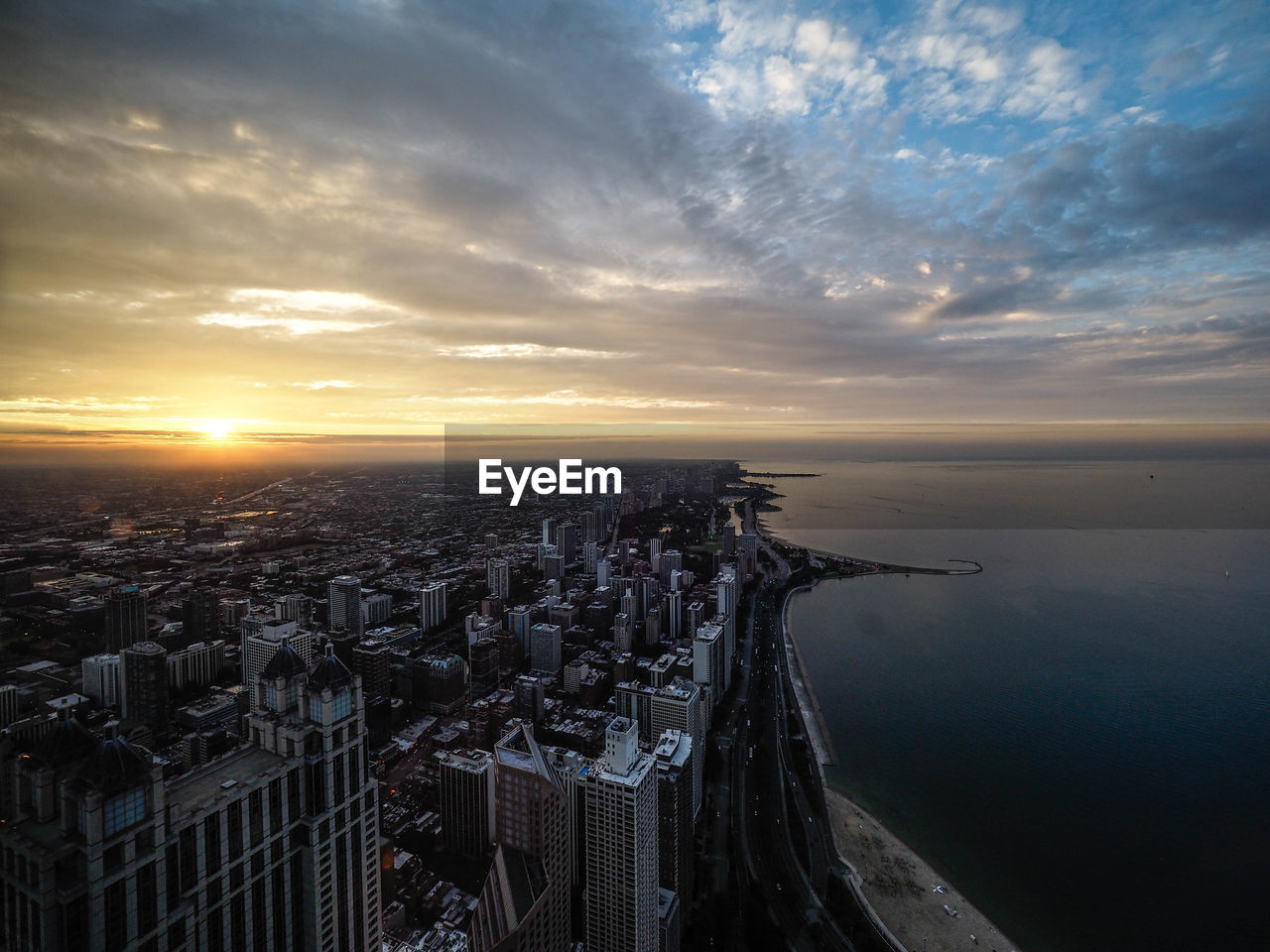 AERIAL VIEW OF BUILDINGS IN CITY AGAINST SKY AT SUNSET