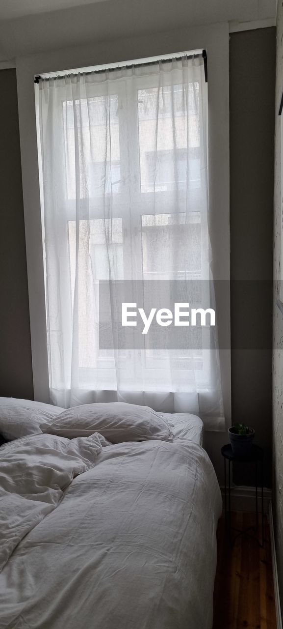 WHITE CURTAIN ON BED IN WINDOW