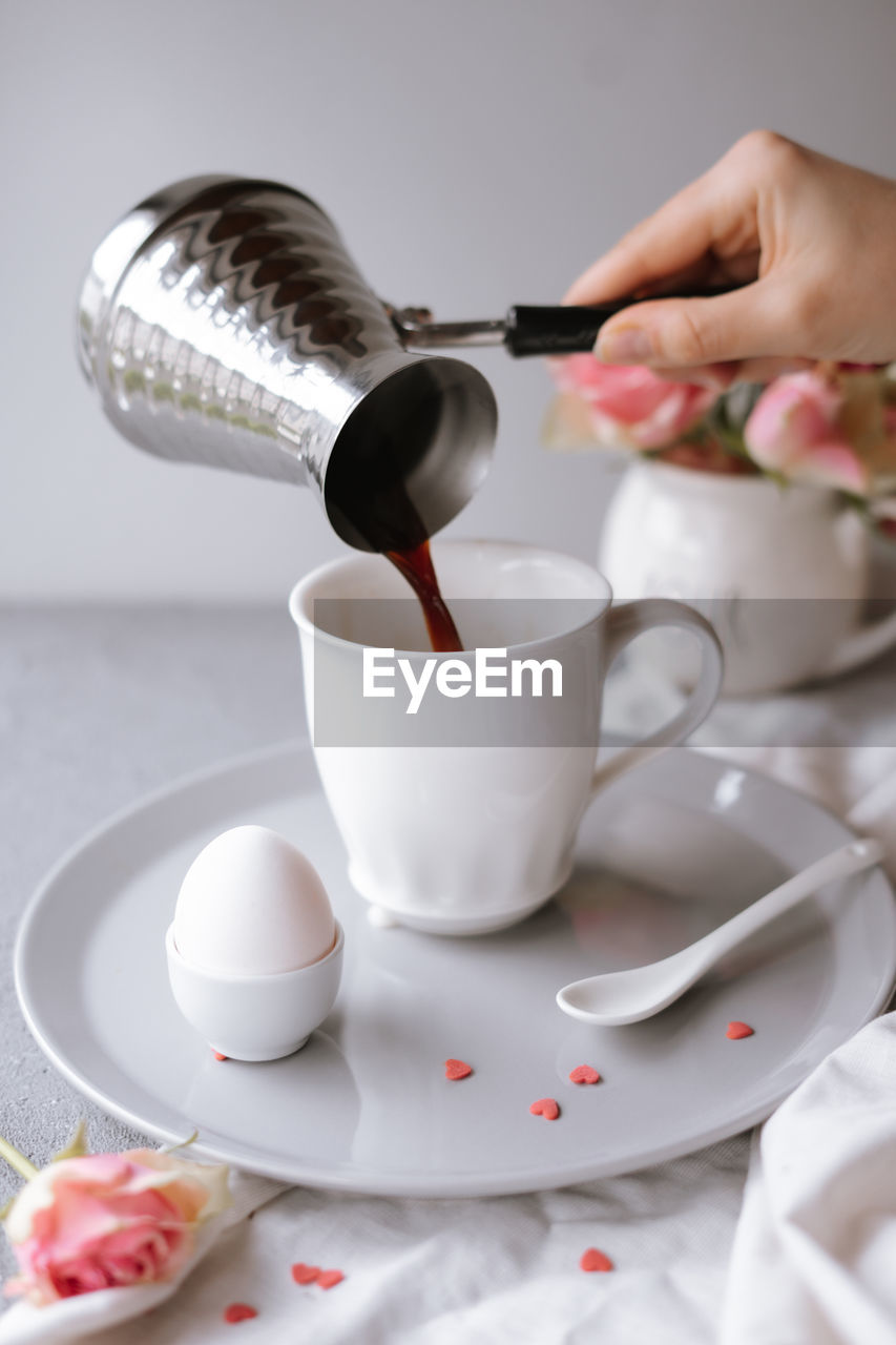 Midsection of person pouring coffee in cup