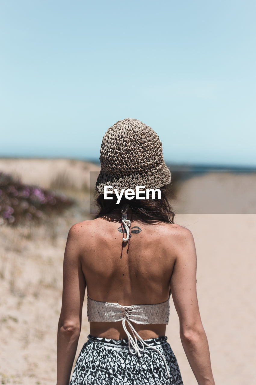 Rear view of woman wearing hat at beach against sky