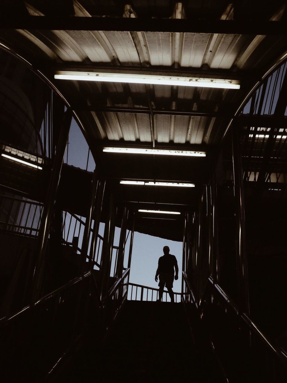 SILHOUETTE MAN WALKING ON STAIRCASE IN CORRIDOR