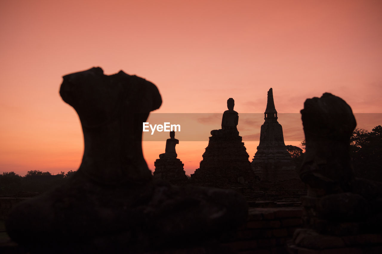 Low angle view of silhouette buddha statues against sky during sunset