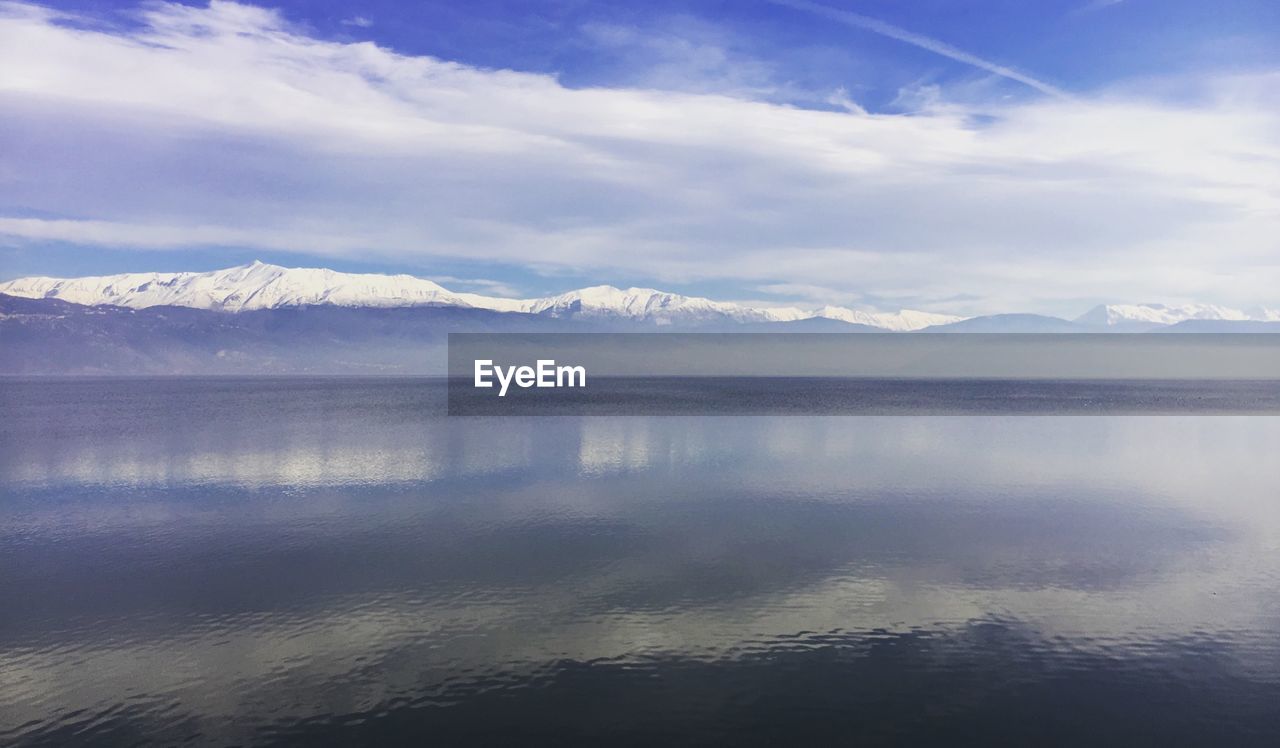 SCENIC VIEW OF LAKE AND MOUNTAINS AGAINST SKY DURING WINTER