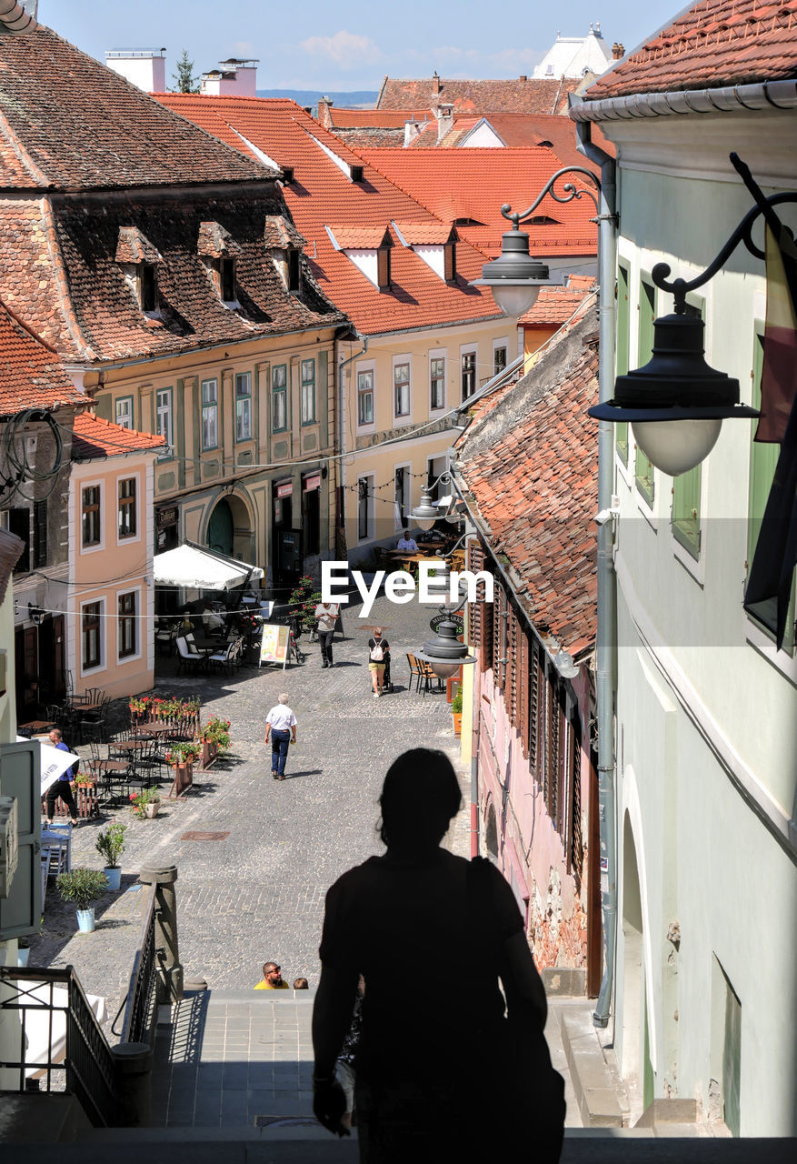 Upper view of a pedestrian street, pasajul scarilor, of sibiu. a woman silhouette in foreground. 
