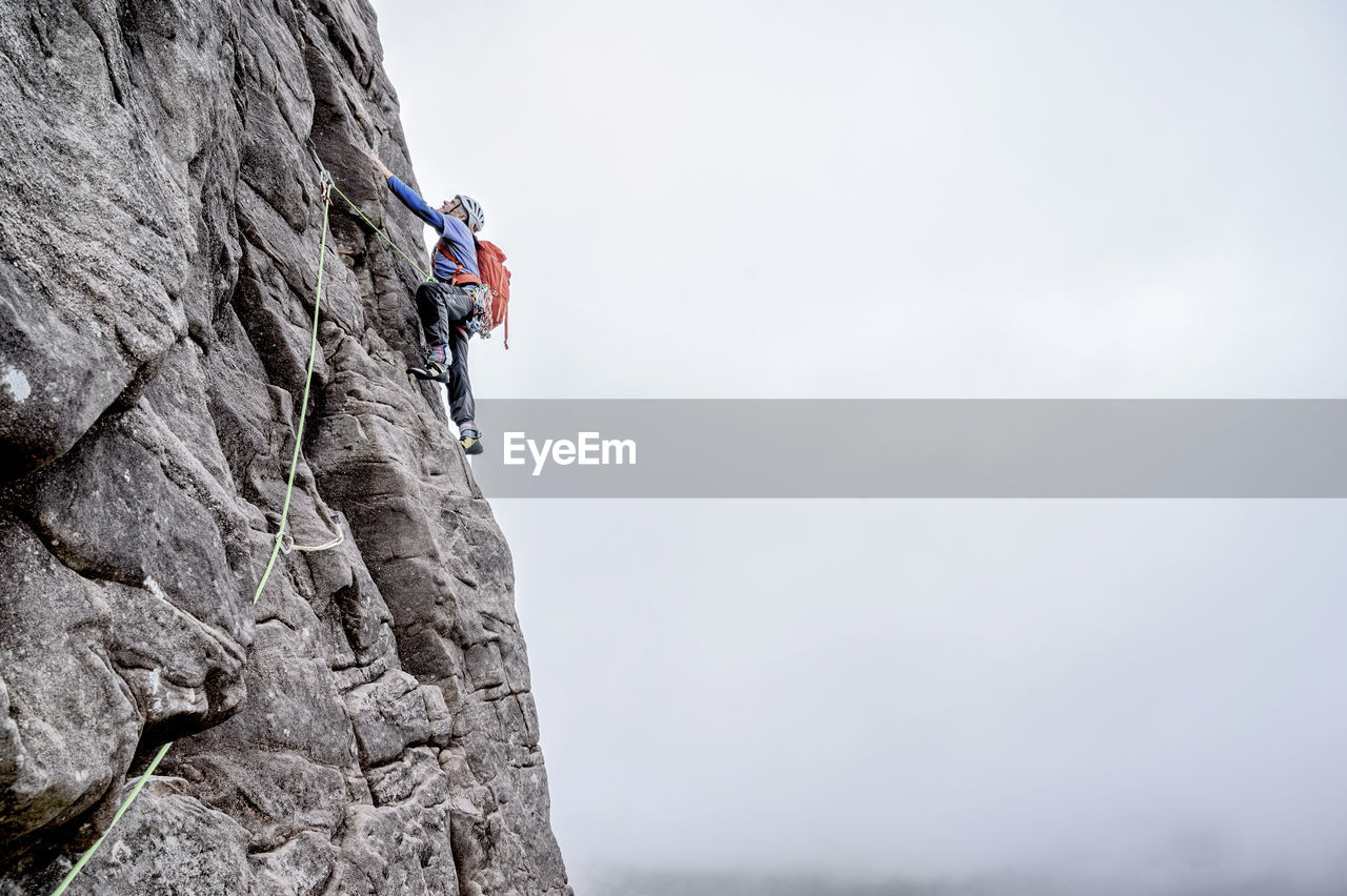 Man with backpack climbing rocky mountain