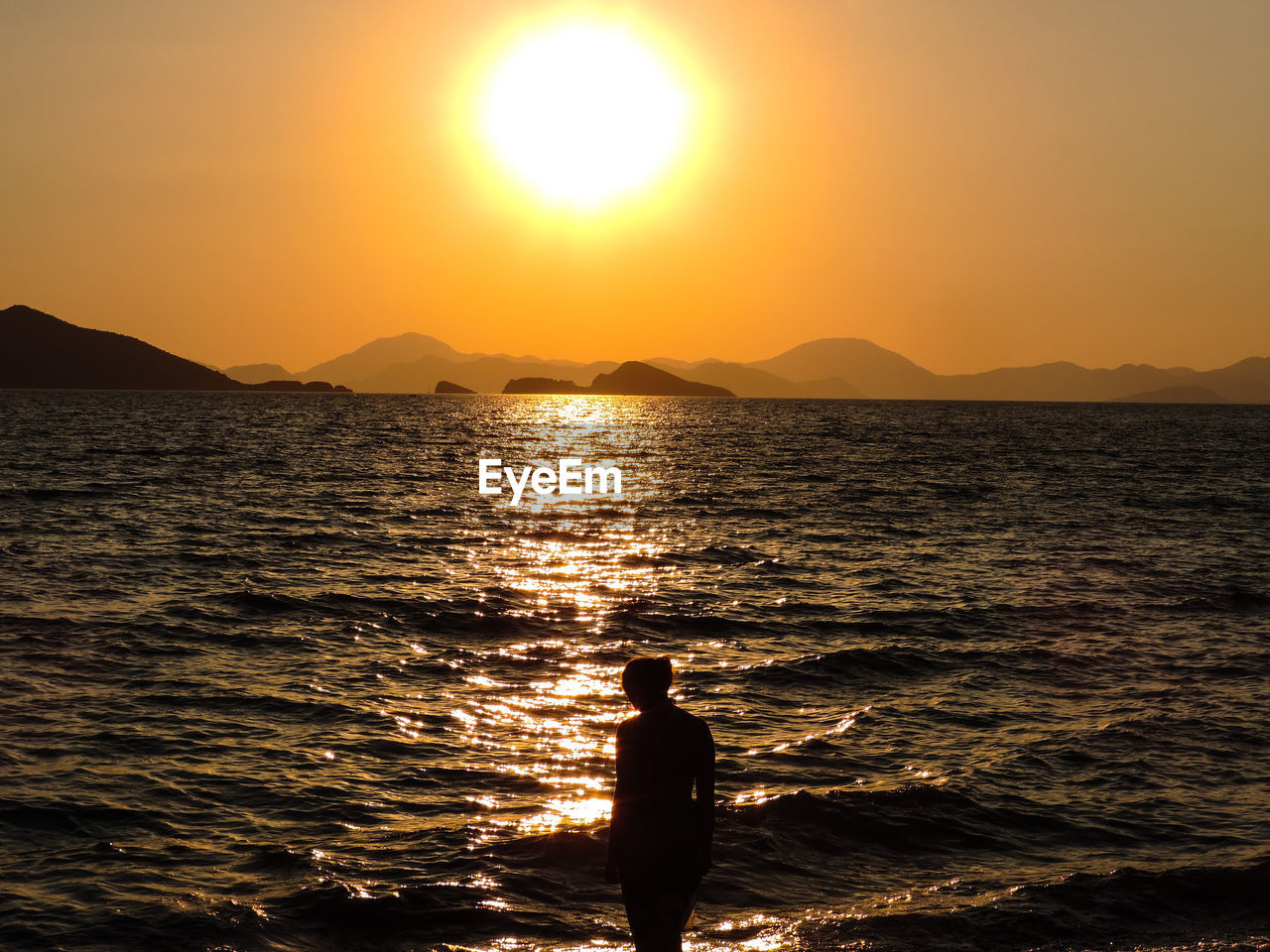 SILHOUETTE WOMAN STANDING ON SEA AGAINST SKY DURING SUNSET