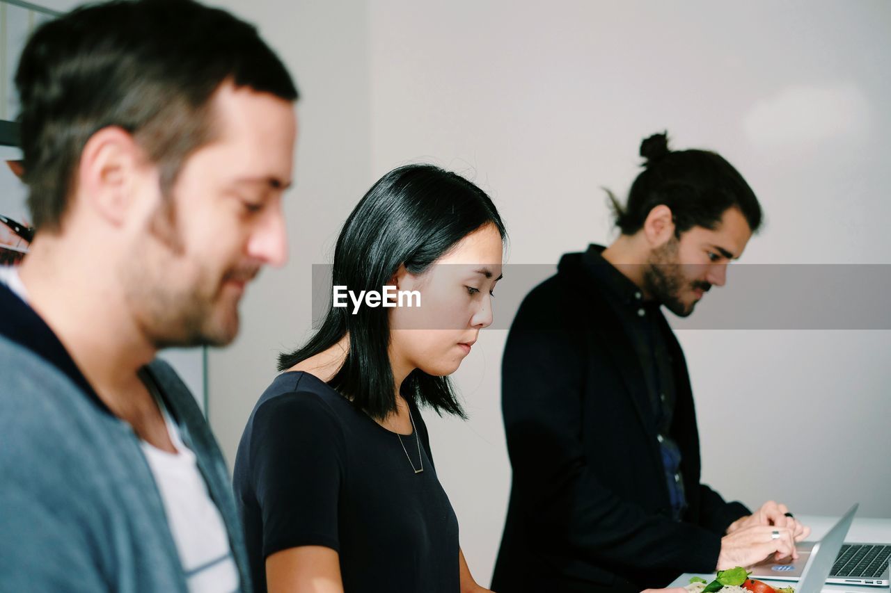 Three people at stand-up desk in office