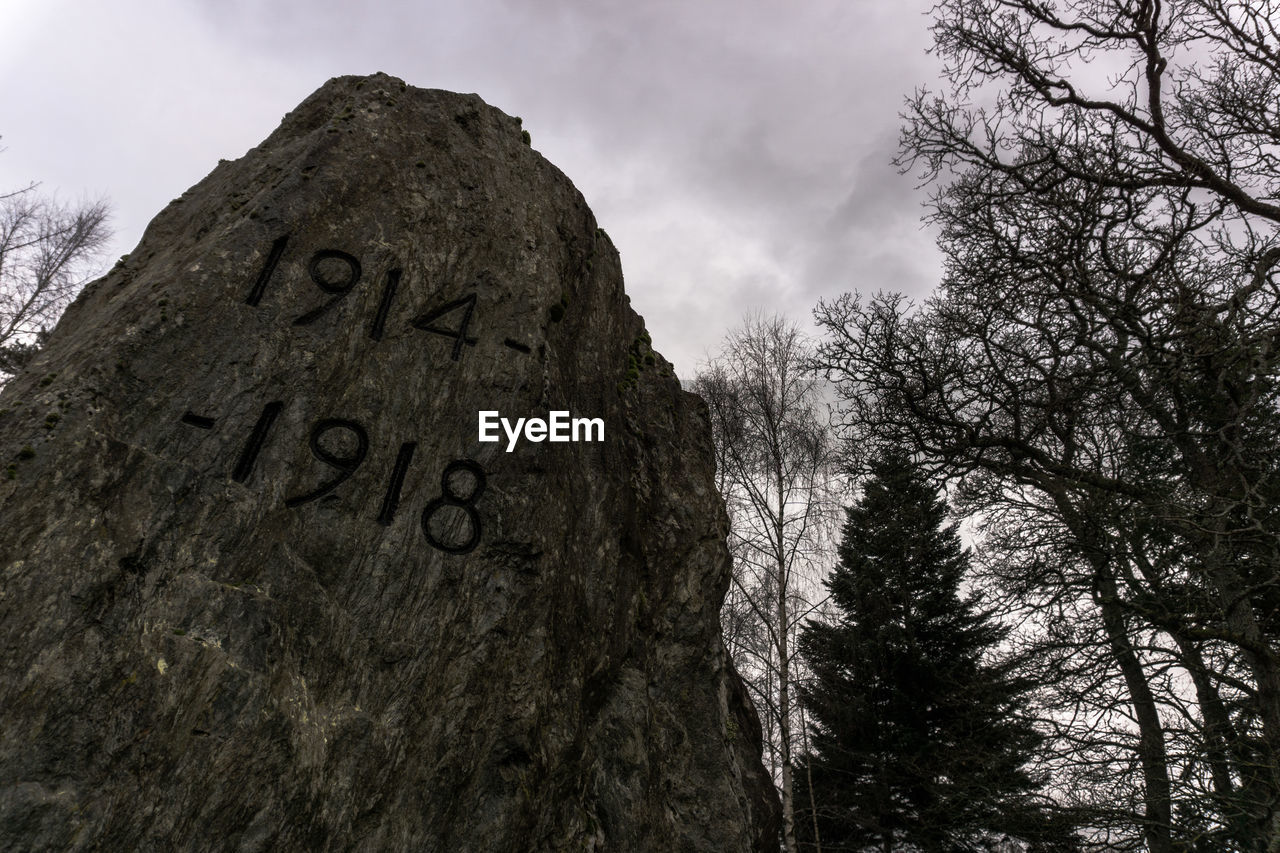 Low angle view of number on rock against sky