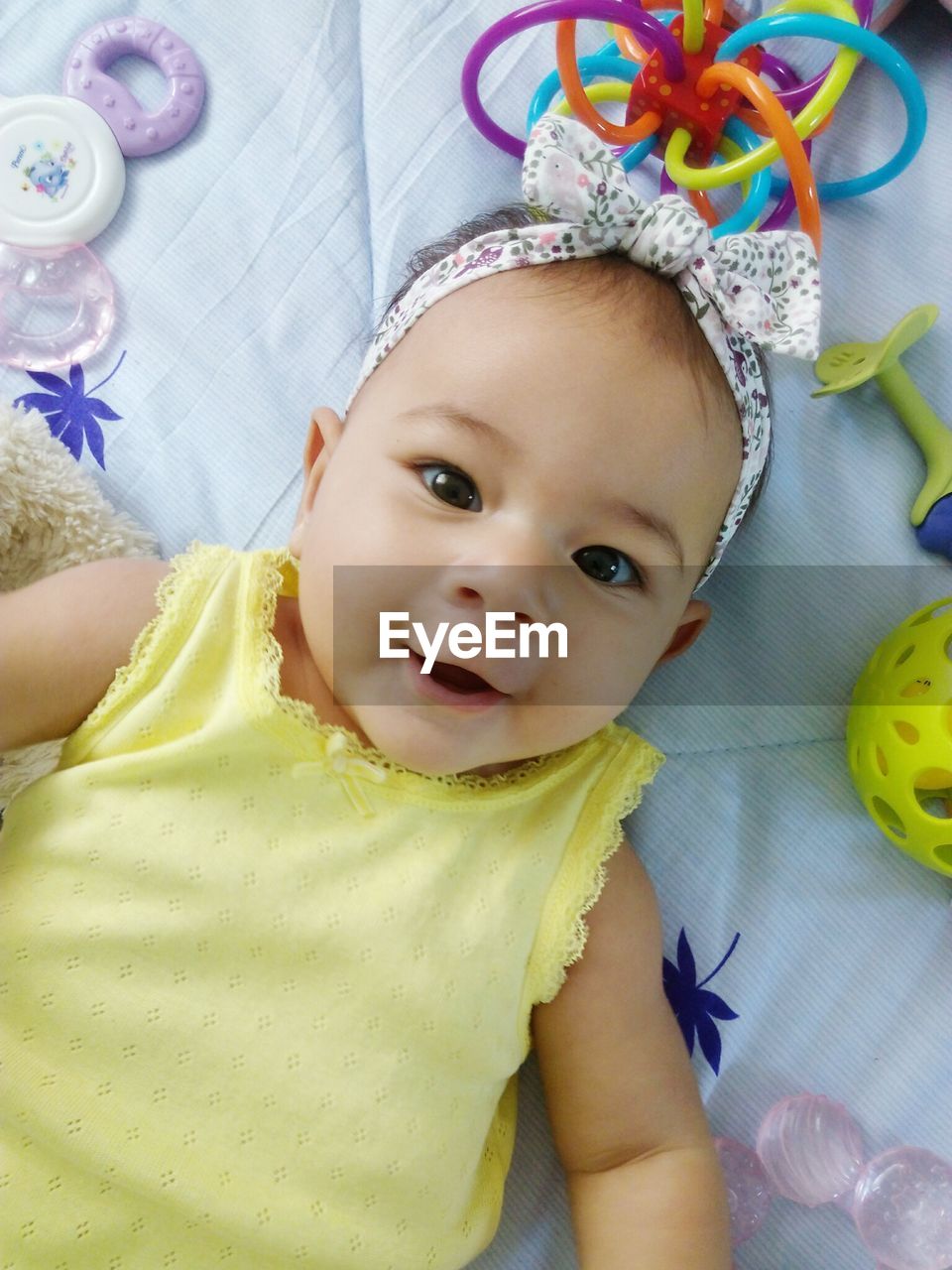 Directly above portrait of baby girl lying on bed