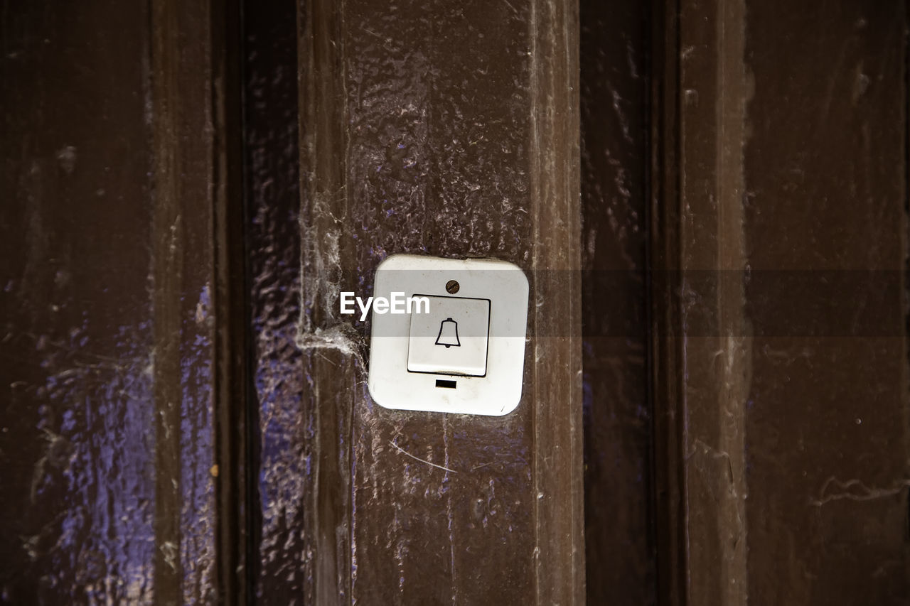 Close-up of doorbell on wooden door