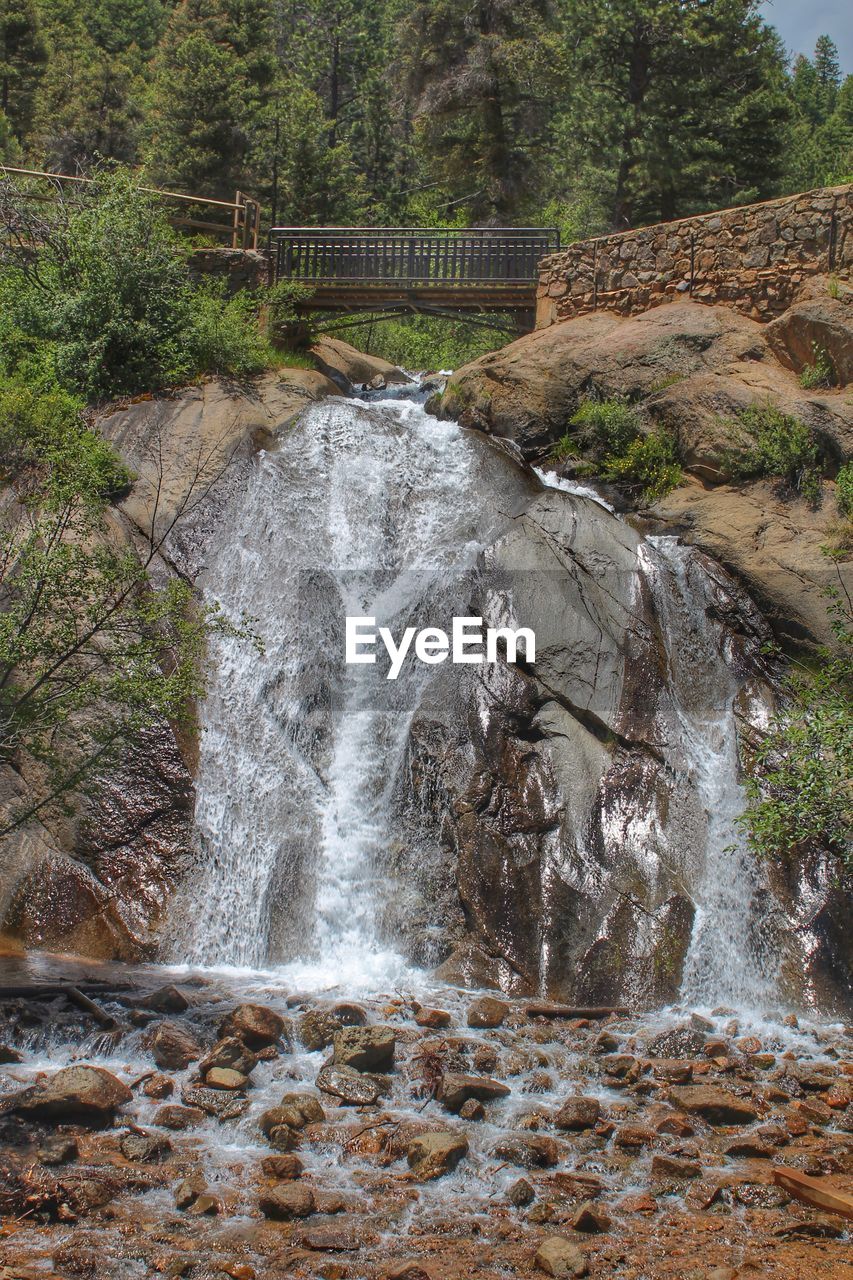 WATER FLOWING OVER RIVER IN FOREST