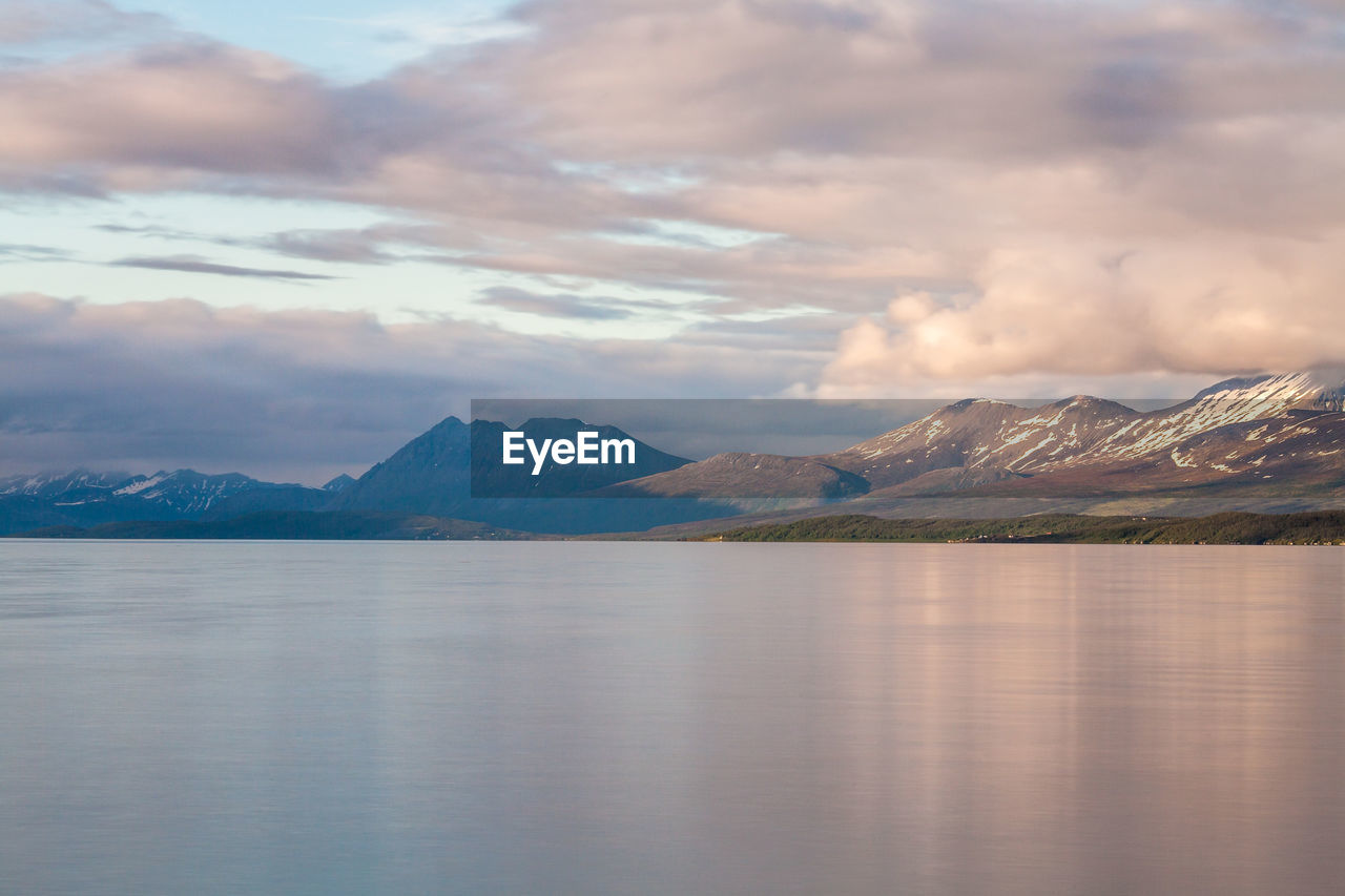 Scenic view of river against cloudy sky