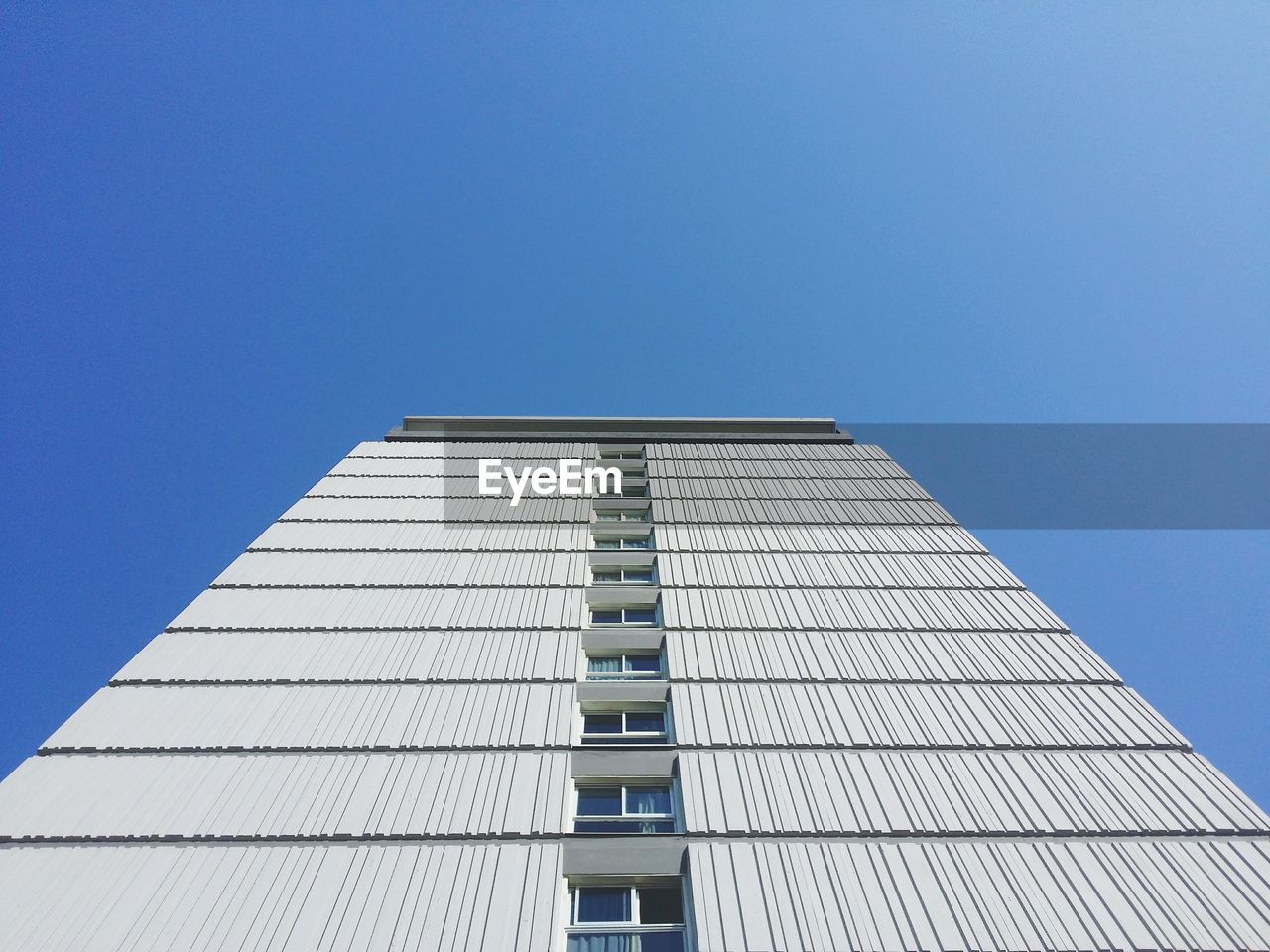 Low angle view of tall building against clear blue sky