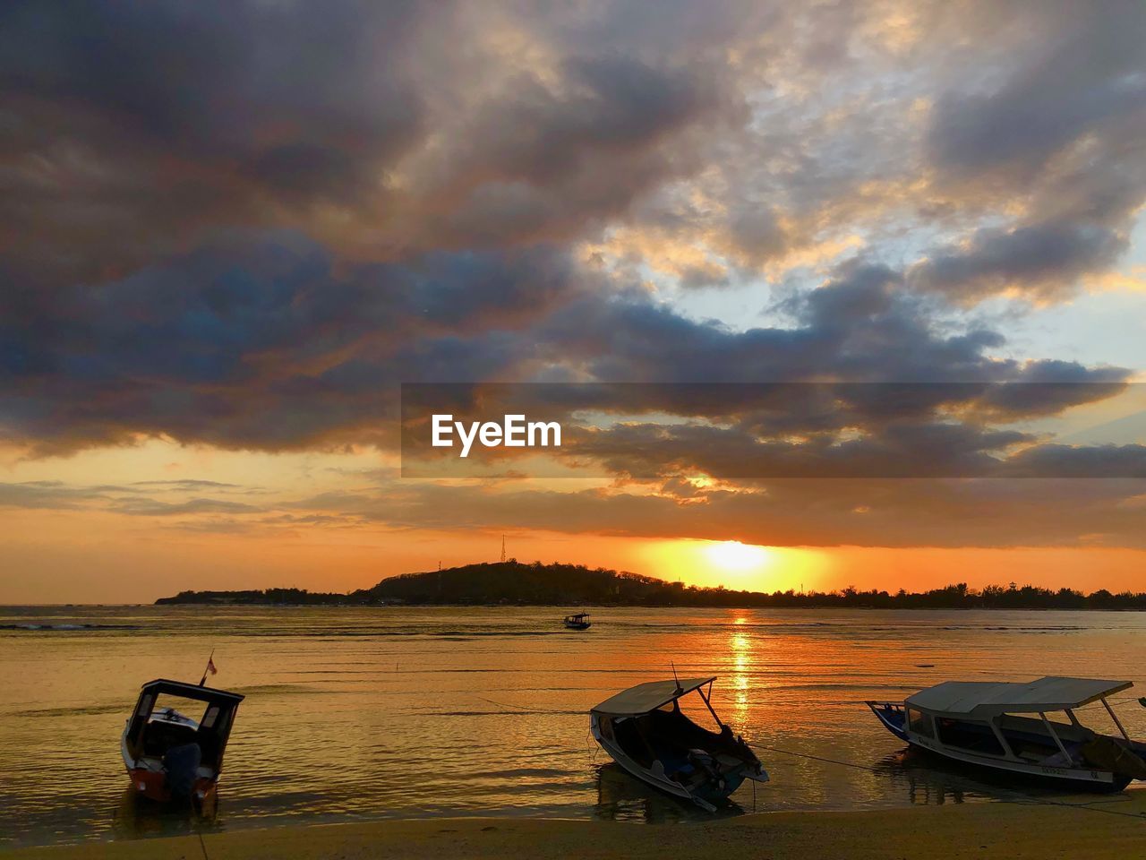 Boat moored in sea against sky during sunset