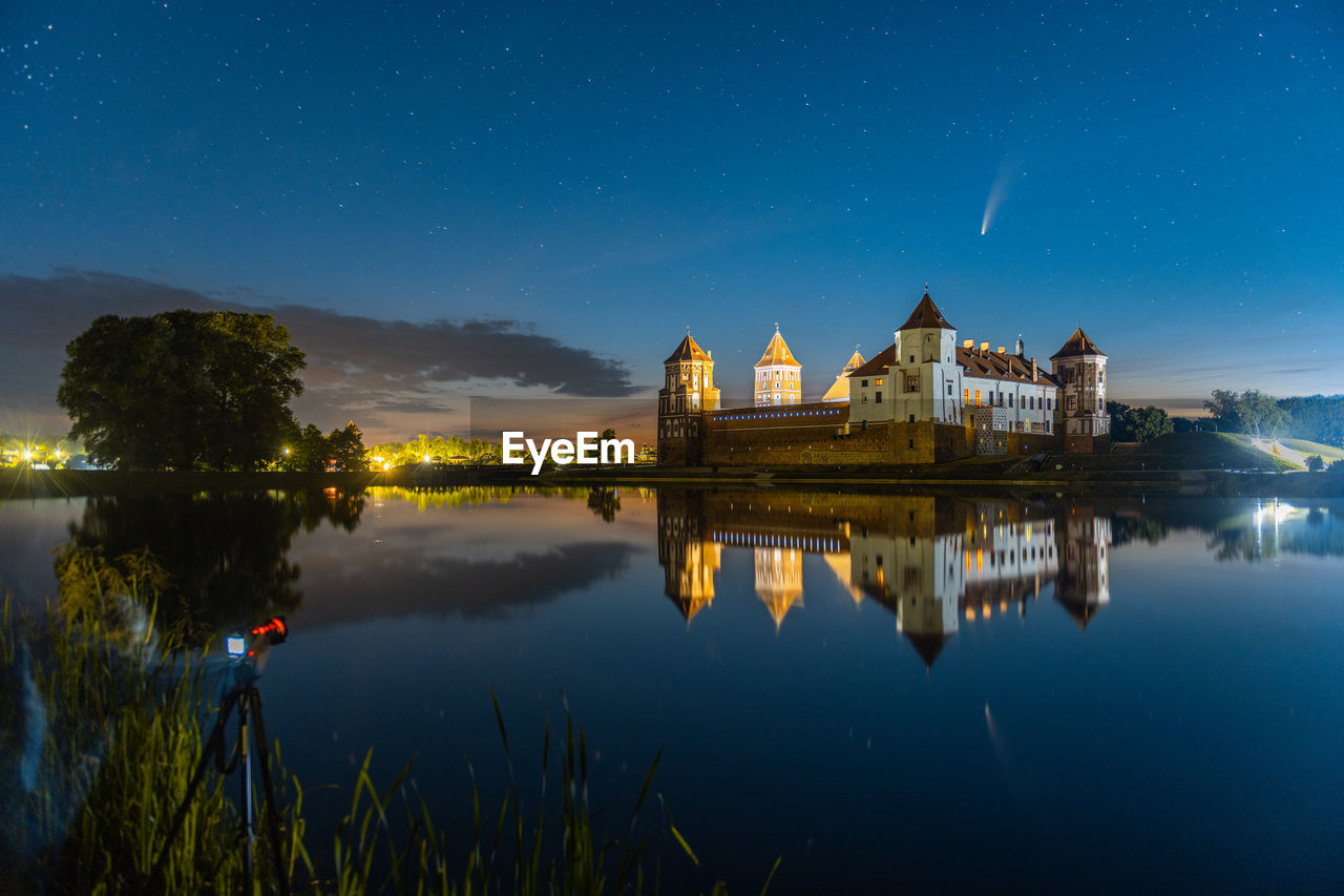 Comet neowise in a night landscape. mir castle in belarus. astronomy.