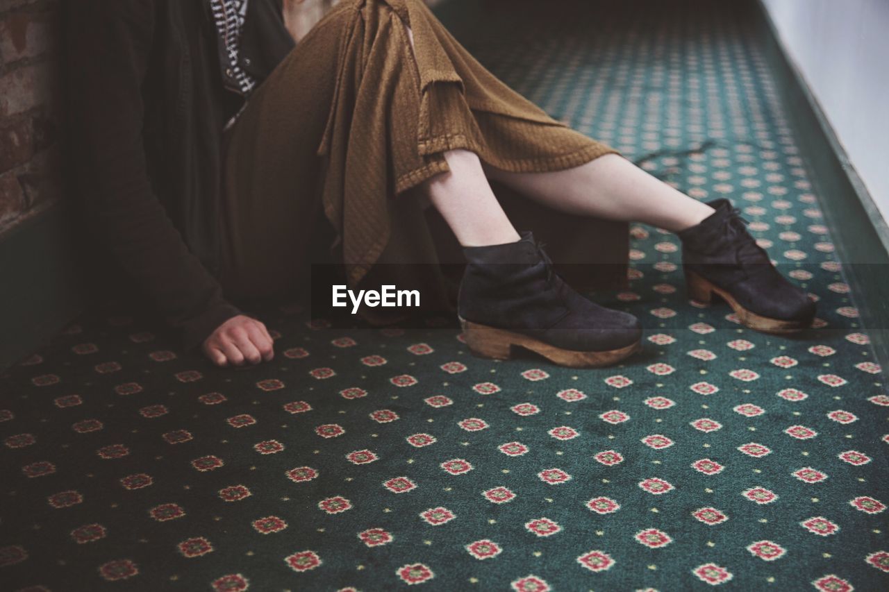 Low section of woman sitting on carpet