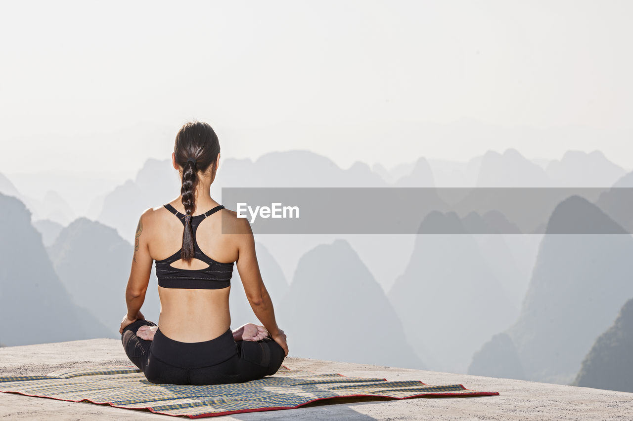 Beautiful woman practising yoga above the kast mountains of yangshuo