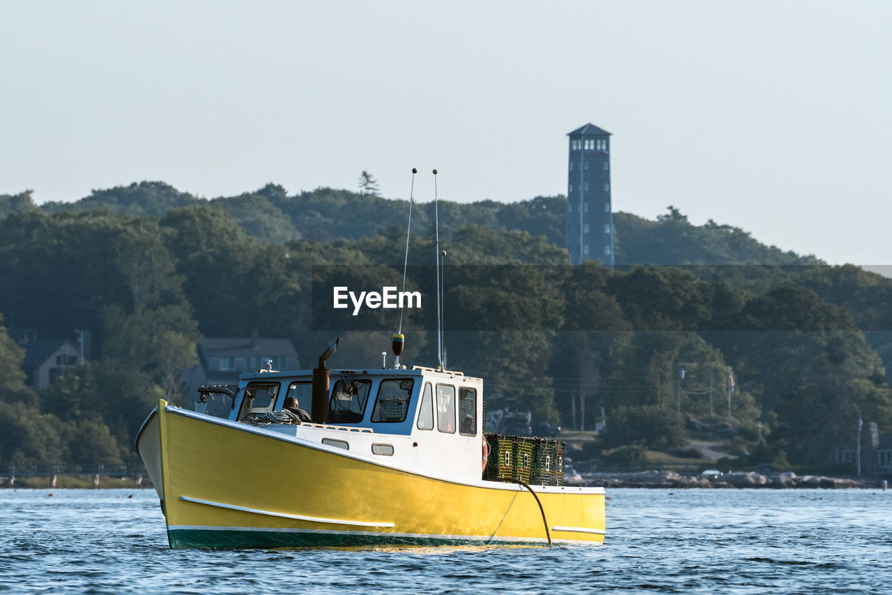 Boat sailing on river against clear sky