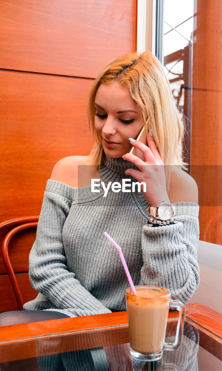 Young woman using phone in cafe